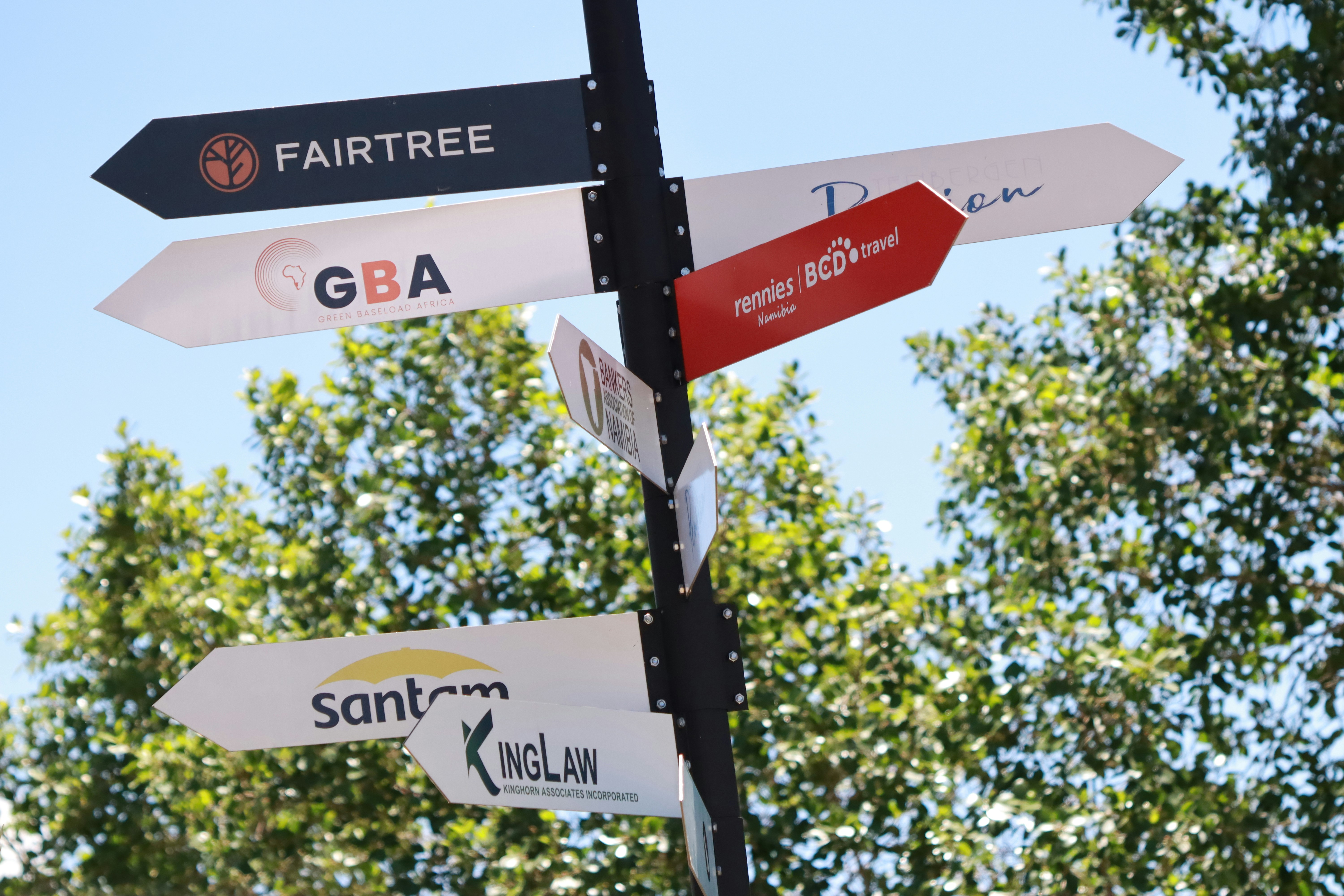 Directional signs with company logos point different ways.