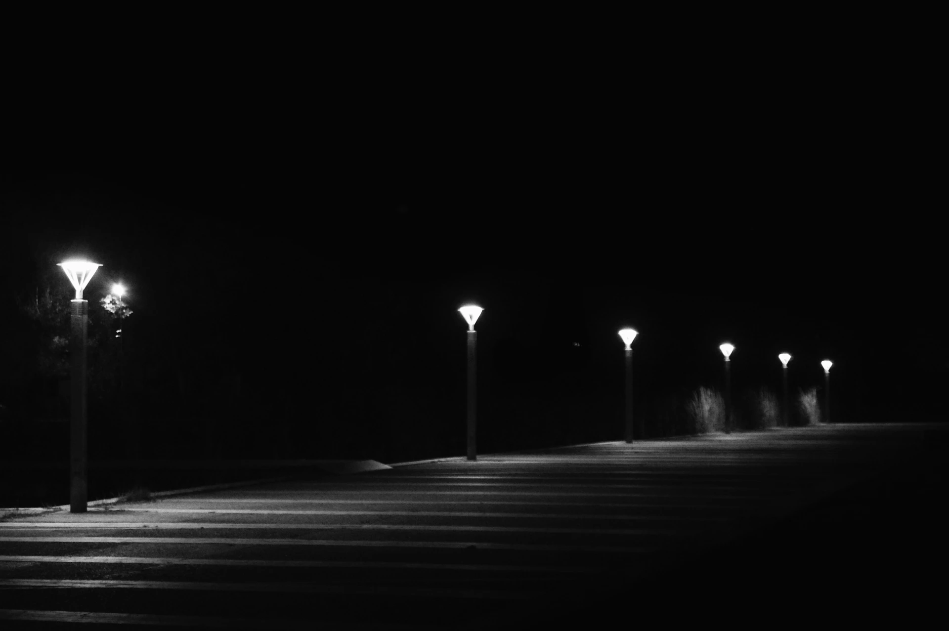 Streetlights illuminate a dark path at night.
