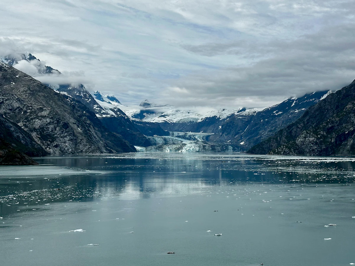 A glacier at the head of a misty fjord between dark mountains