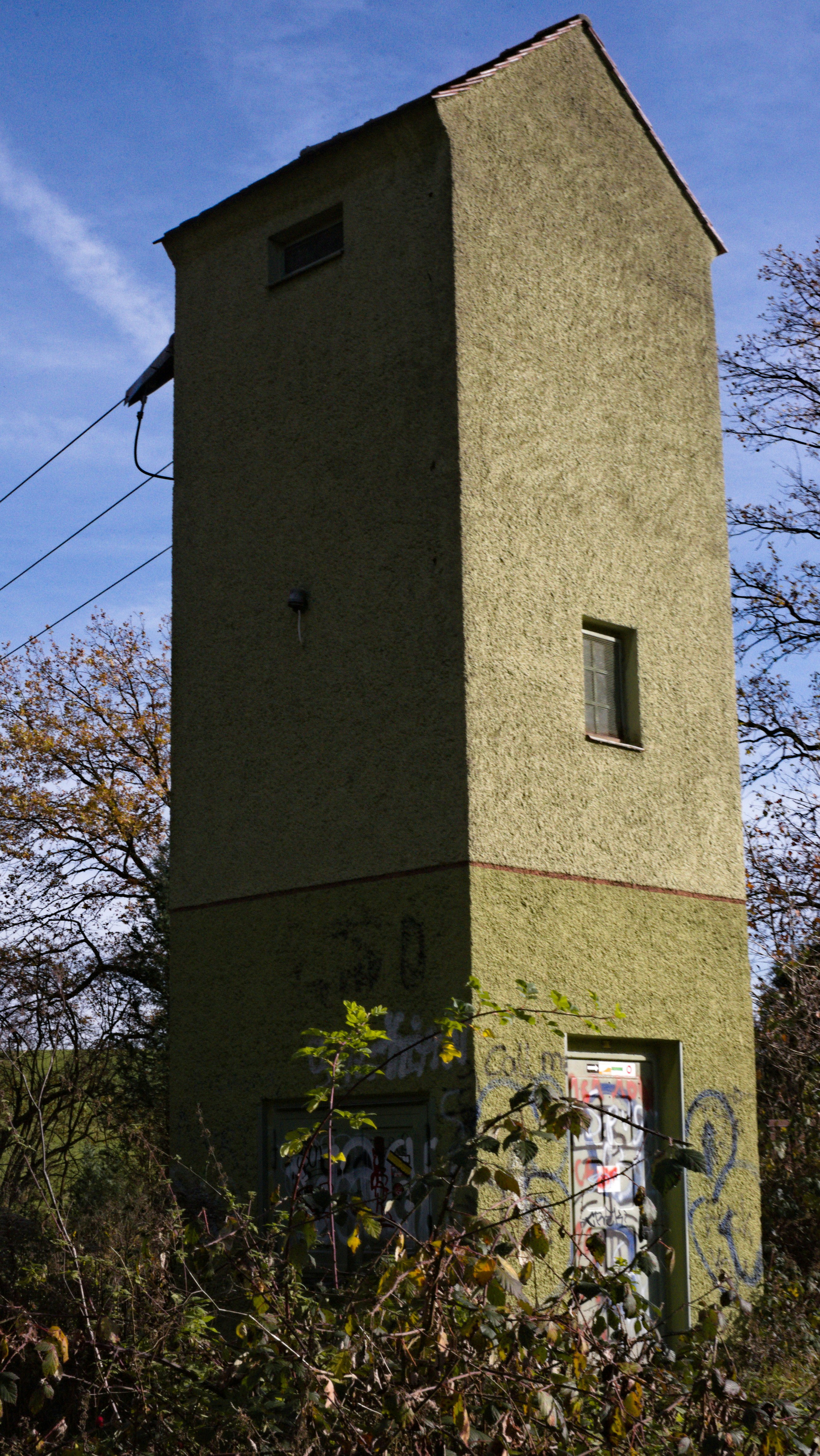 Tall, weathered building with graffiti and overgrown vegetation.