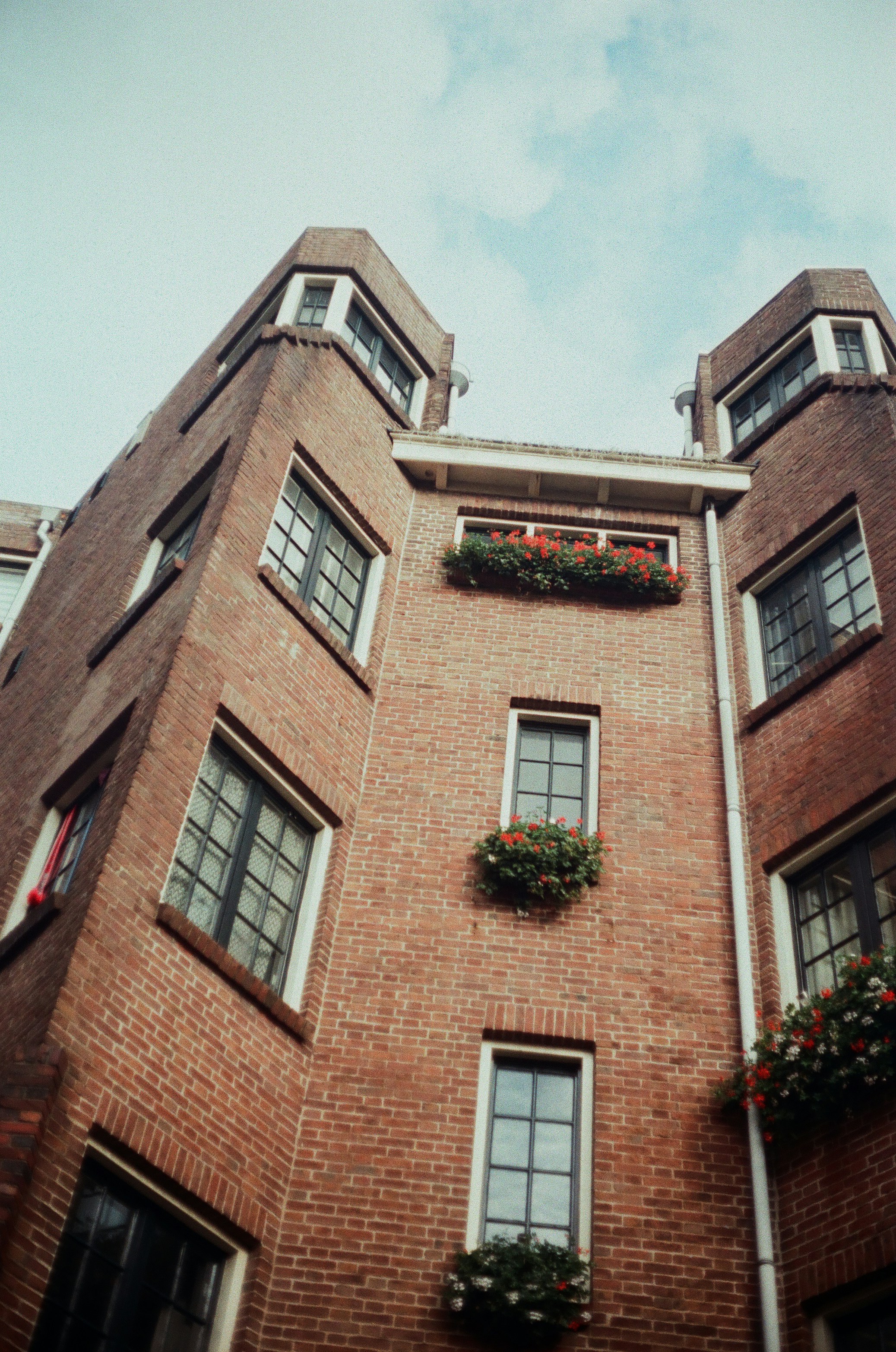 Backsteingebäude mit Fenstern und Blumenkästen