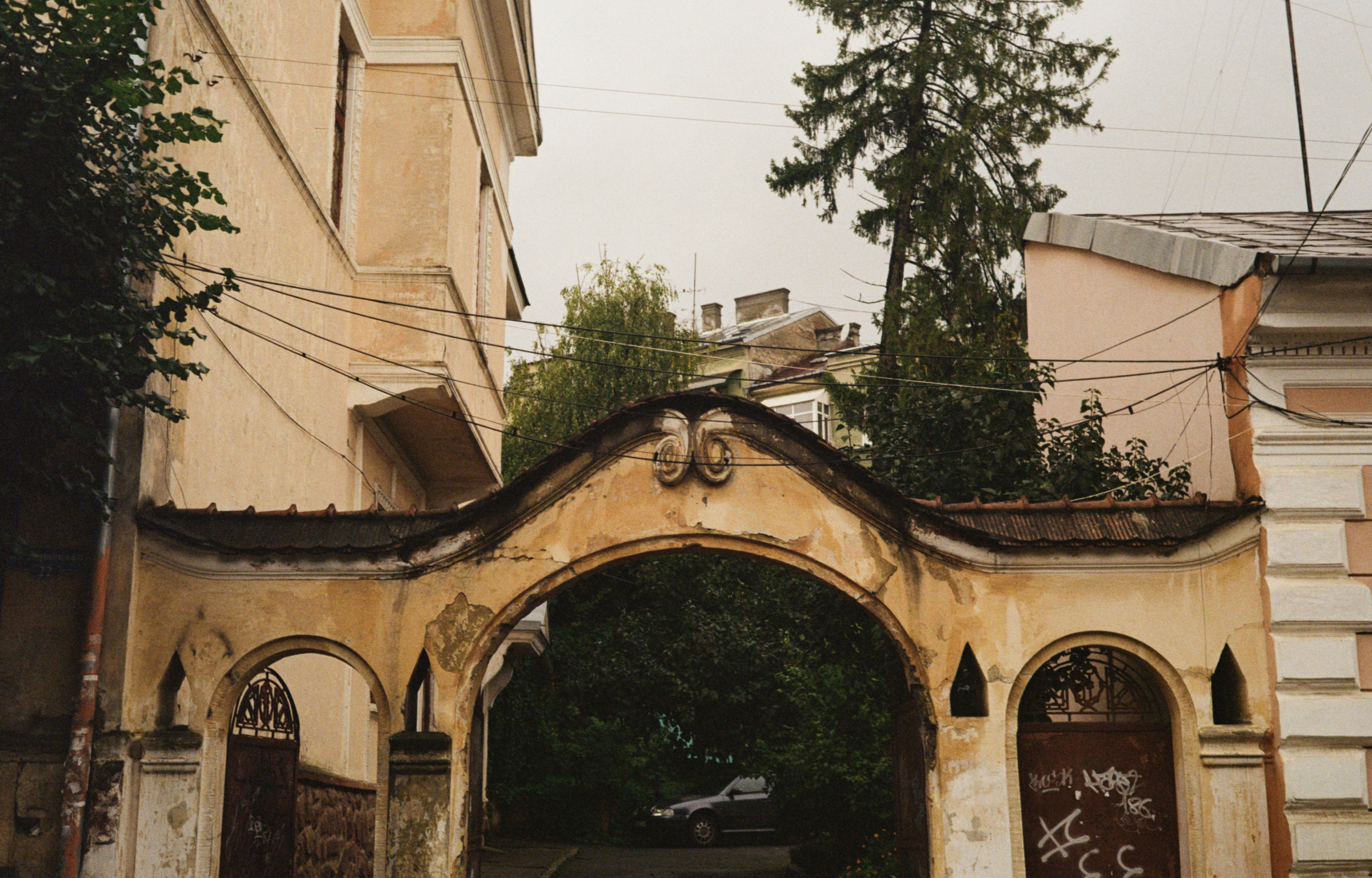 An old archway with ornate details and trees.