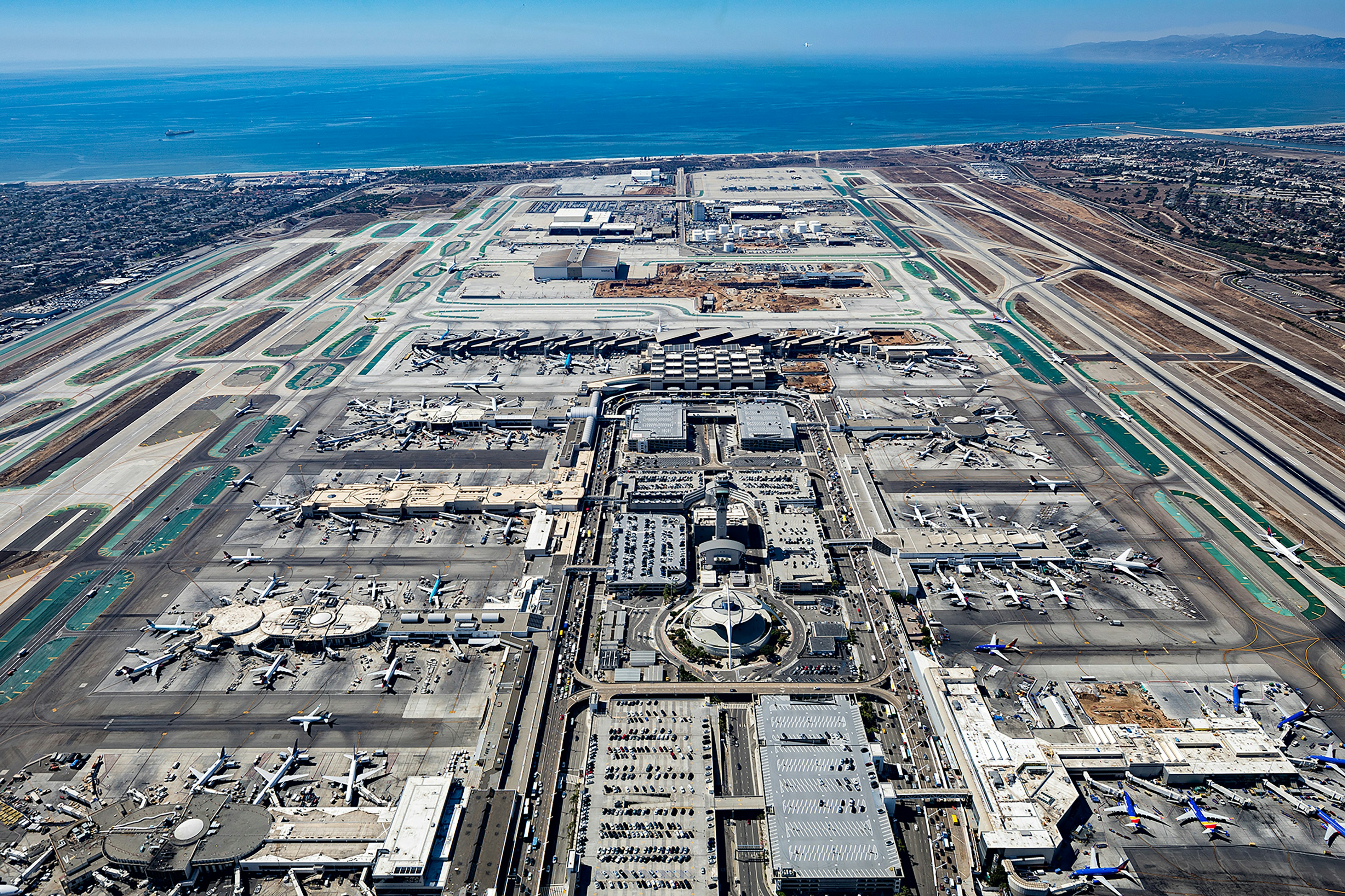Vista aérea de un gran aeropuerto con el océano de fondo.