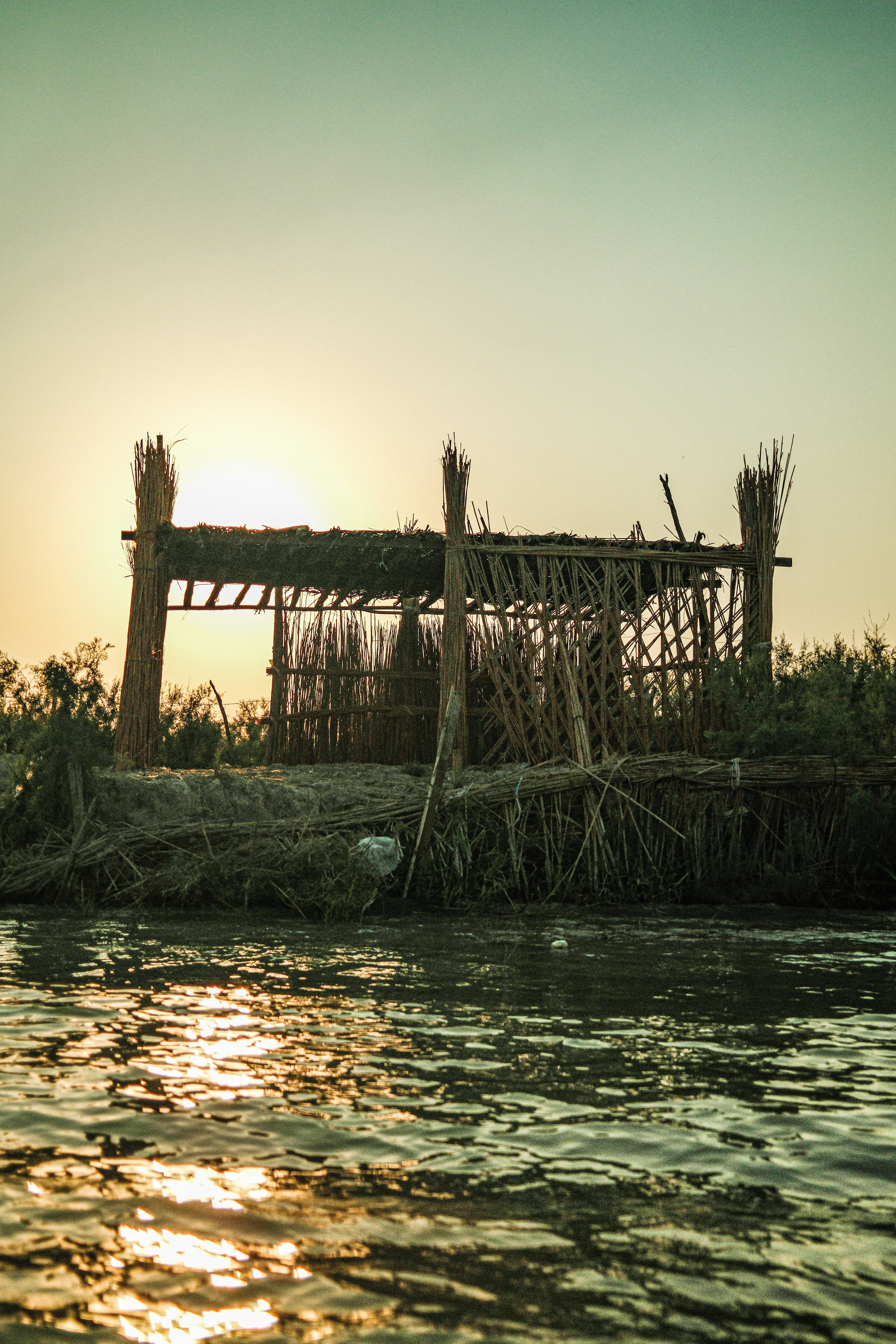 Rustic hut on a riverbank at sunset