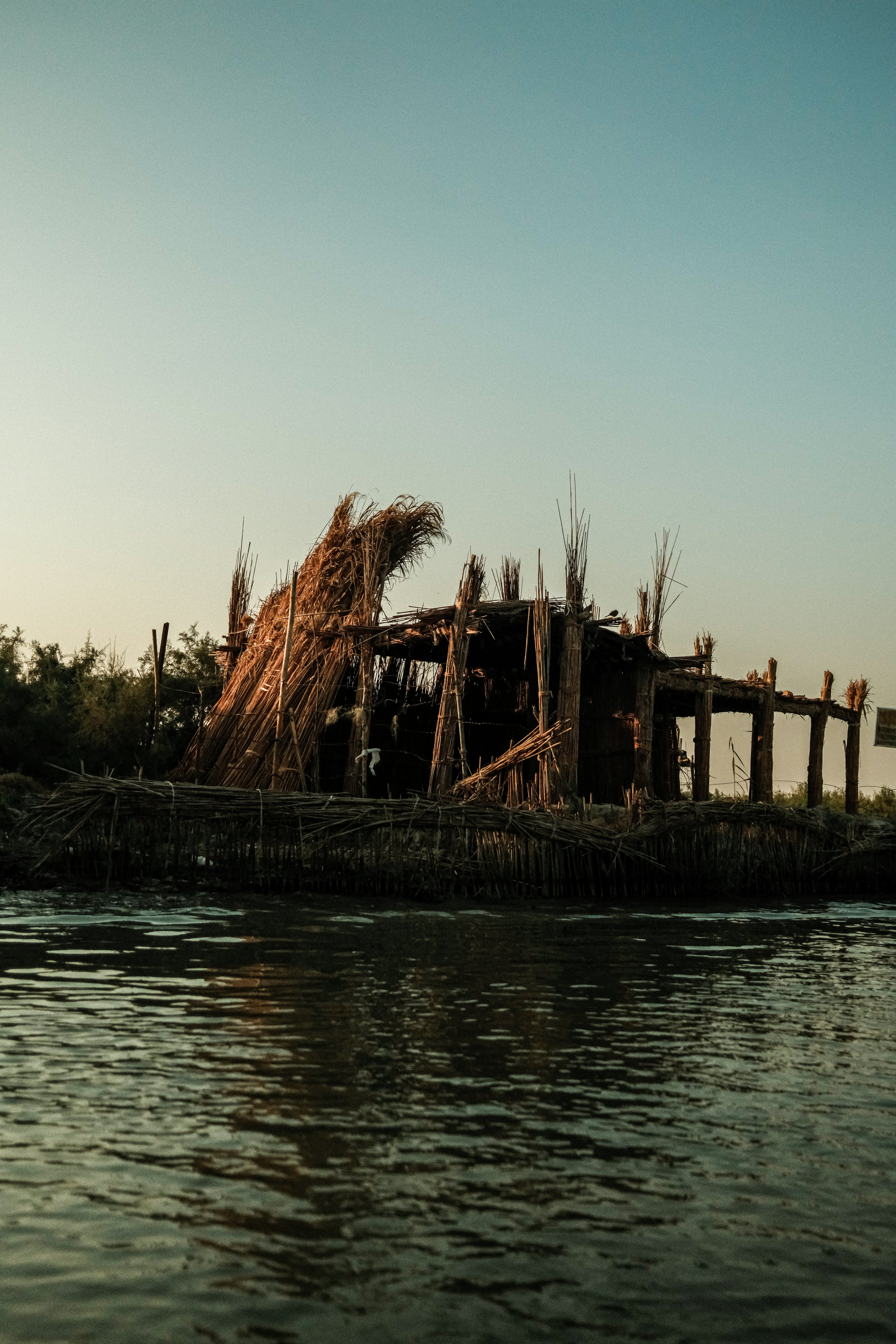 Dilapidated hut on a riverbank at sunset