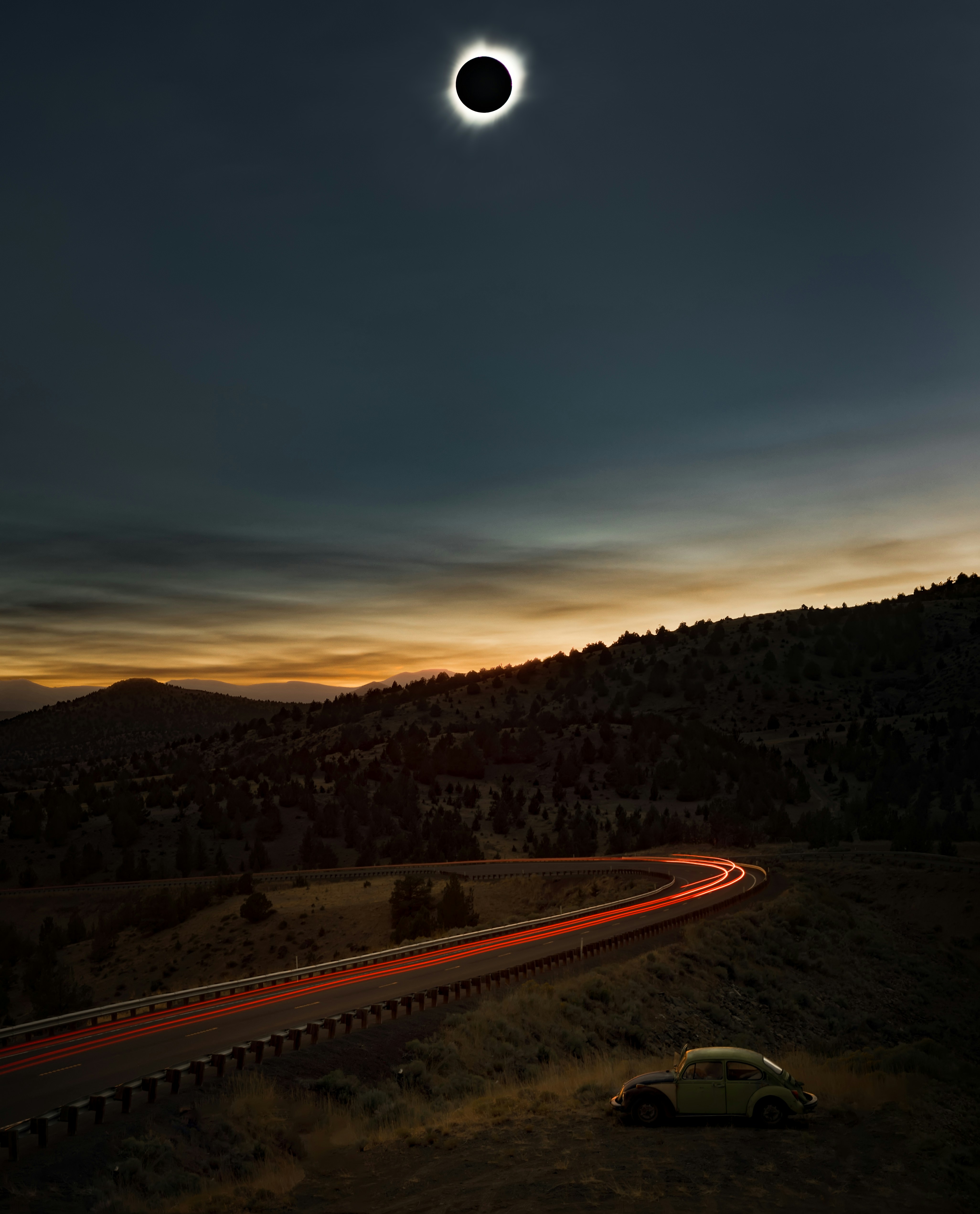 Eclipse solar total sobre una carretera sinuosa al anochecer.