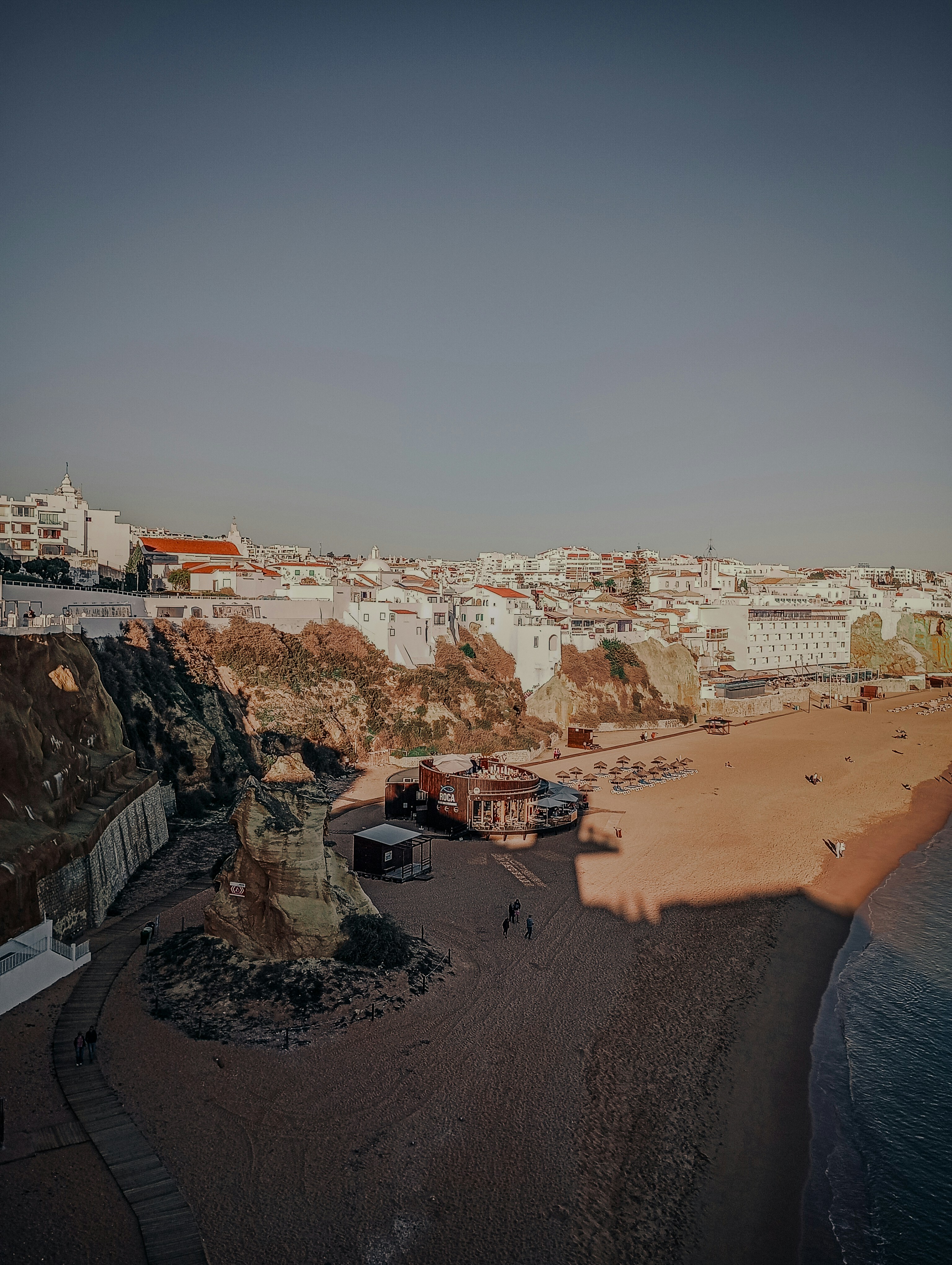Città costiera con edifici bianchi su scogliere sopra una spiaggia sabbiosa.