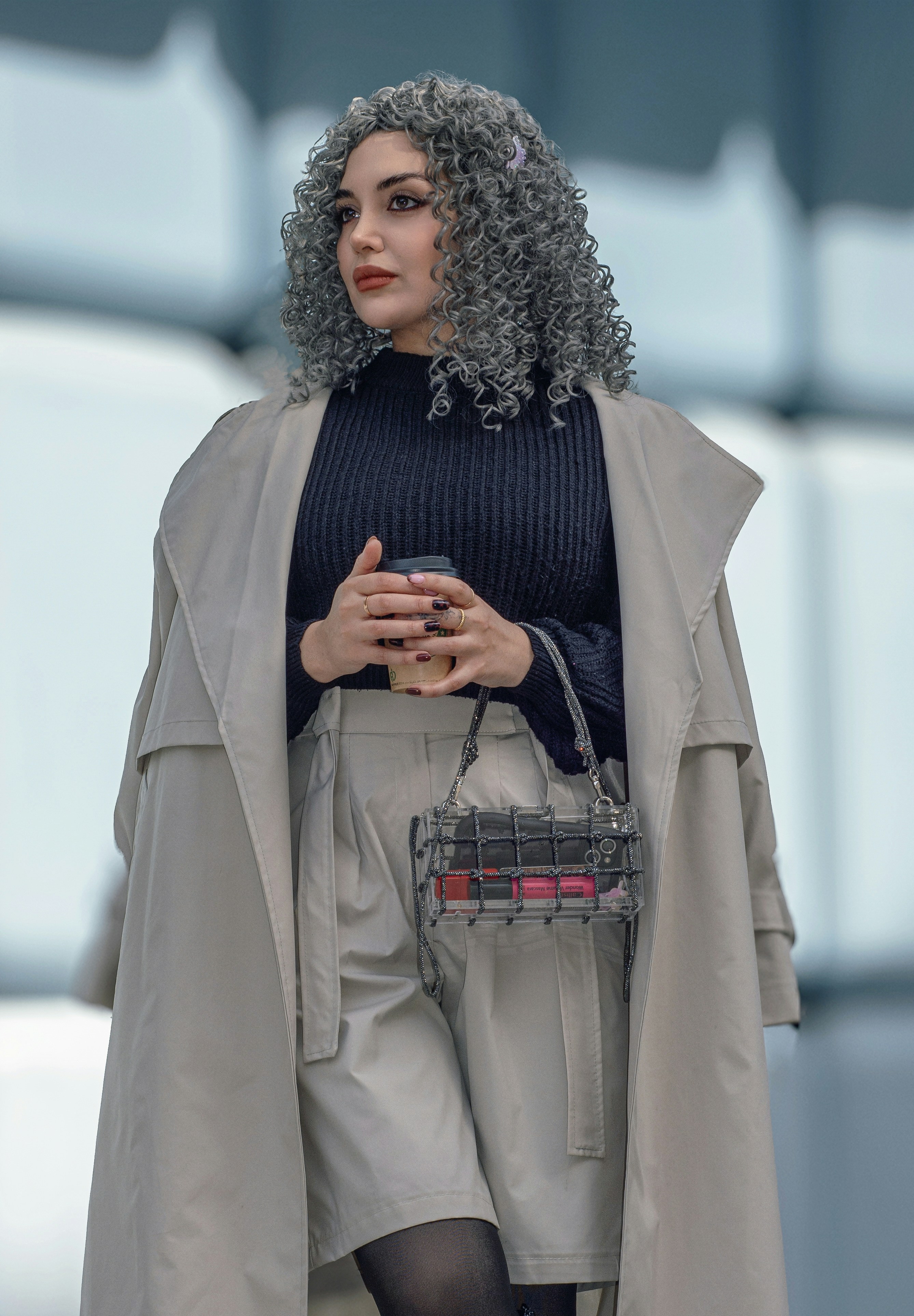 Woman with curly gray hair holding a coffee cup.
