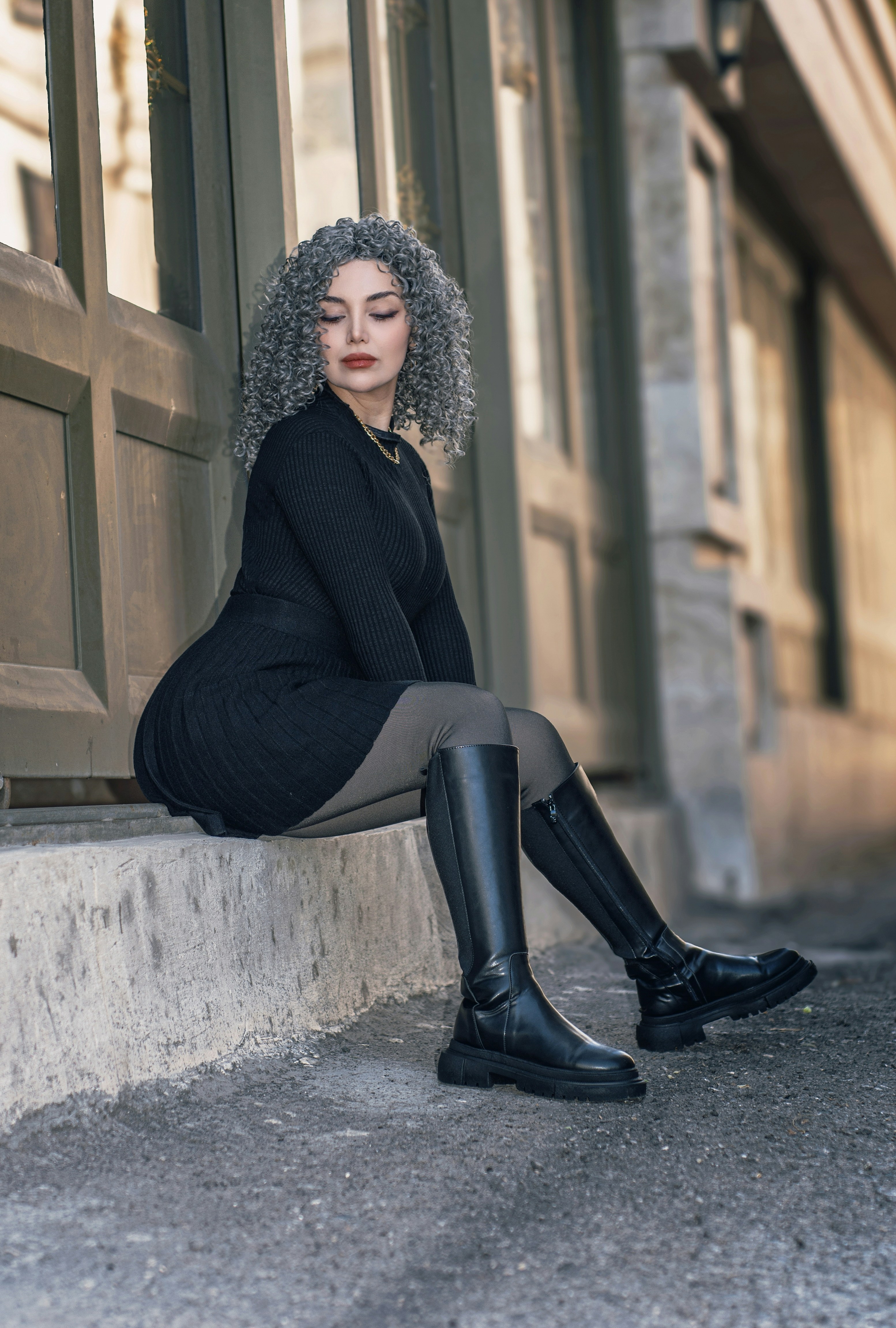 Woman with curly grey hair sitting by a doorway