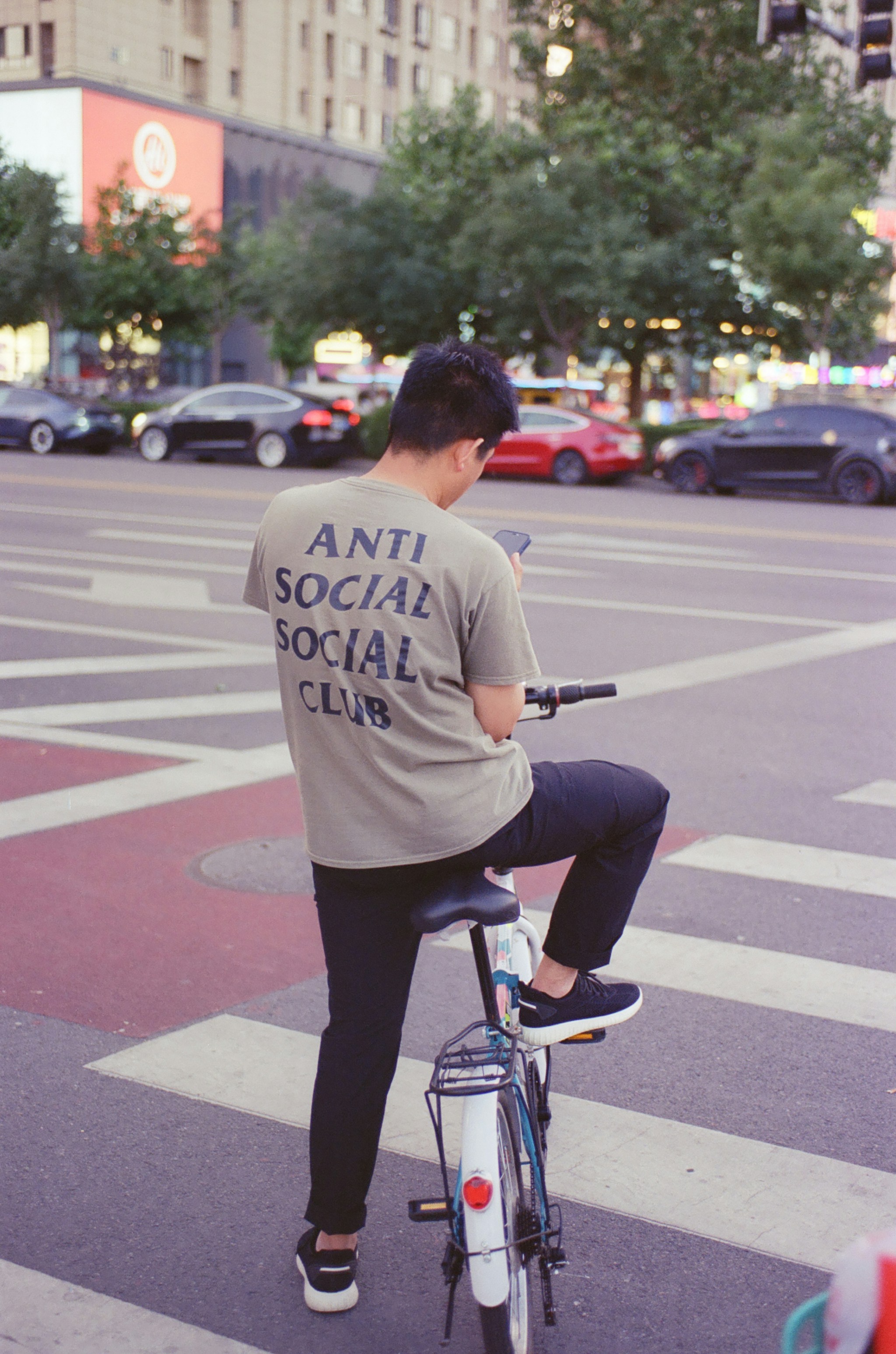 Man wearing "anti social social club" shirt on bicycle