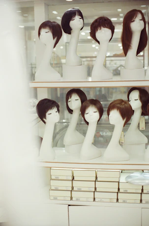 Mannequins display various wigs on shelves.