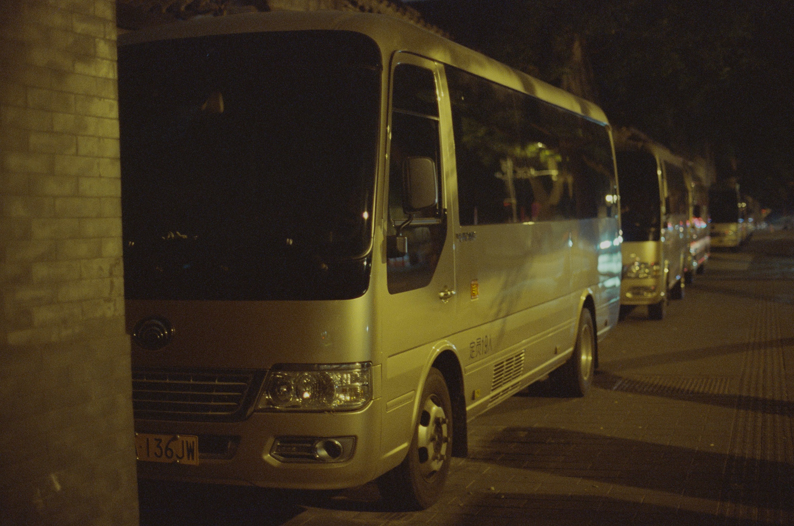Several buses parked on a street at night