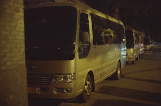 Several buses parked on a street at night