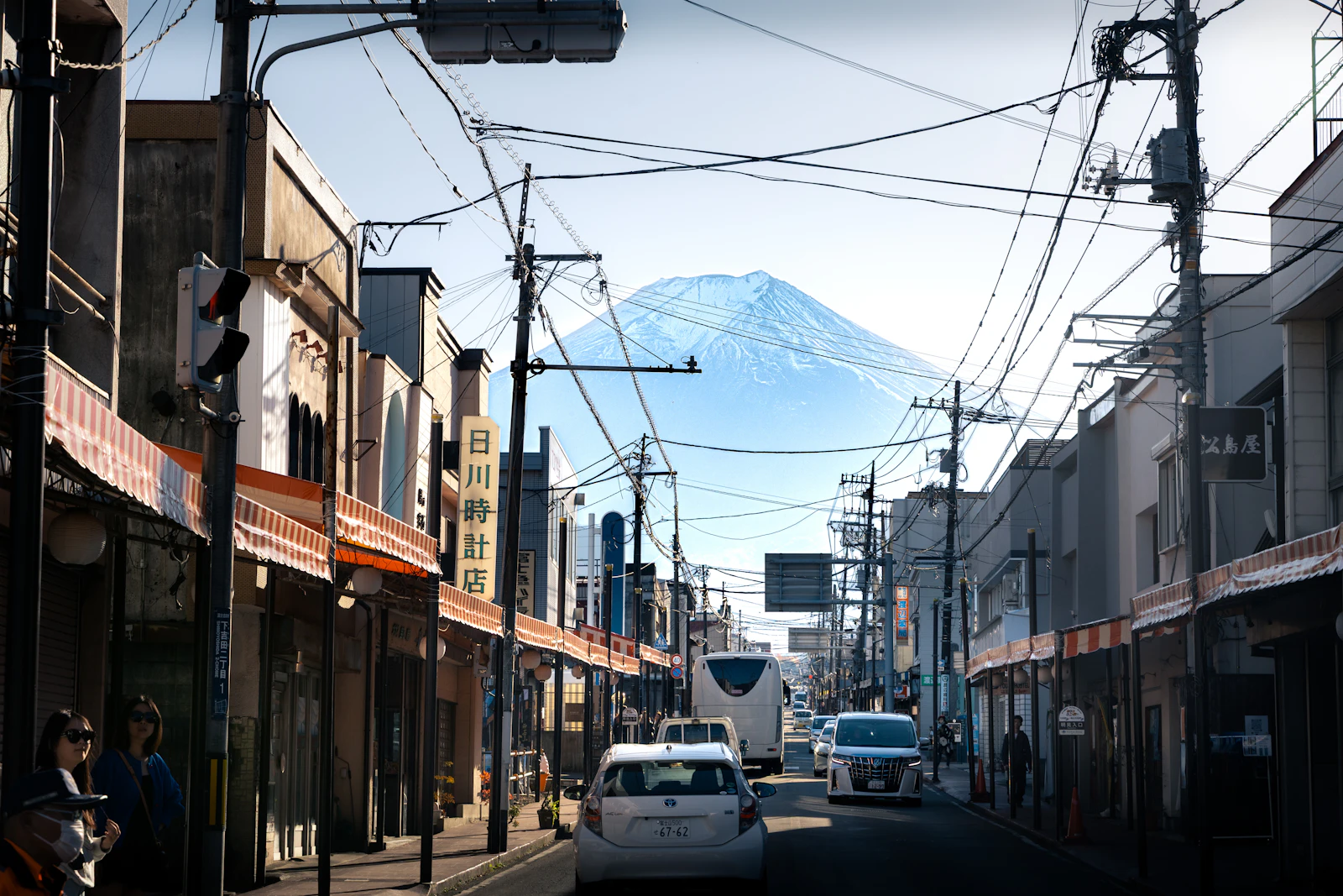 Traffic moves along a Japanese road with Mount Fuji beyond the town