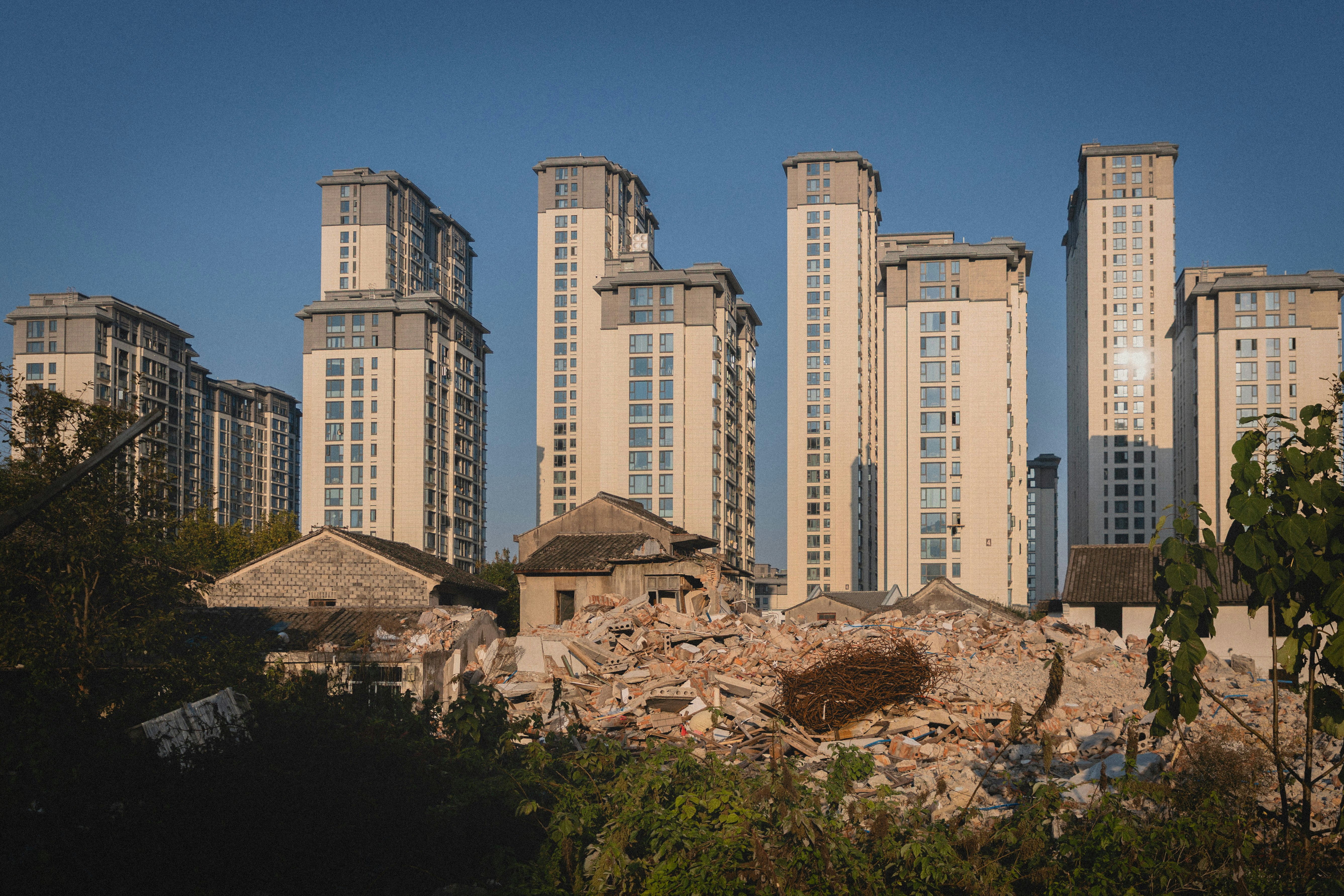 Prédios modernos de apartamentos se erguem acima de pilhas de escombros.