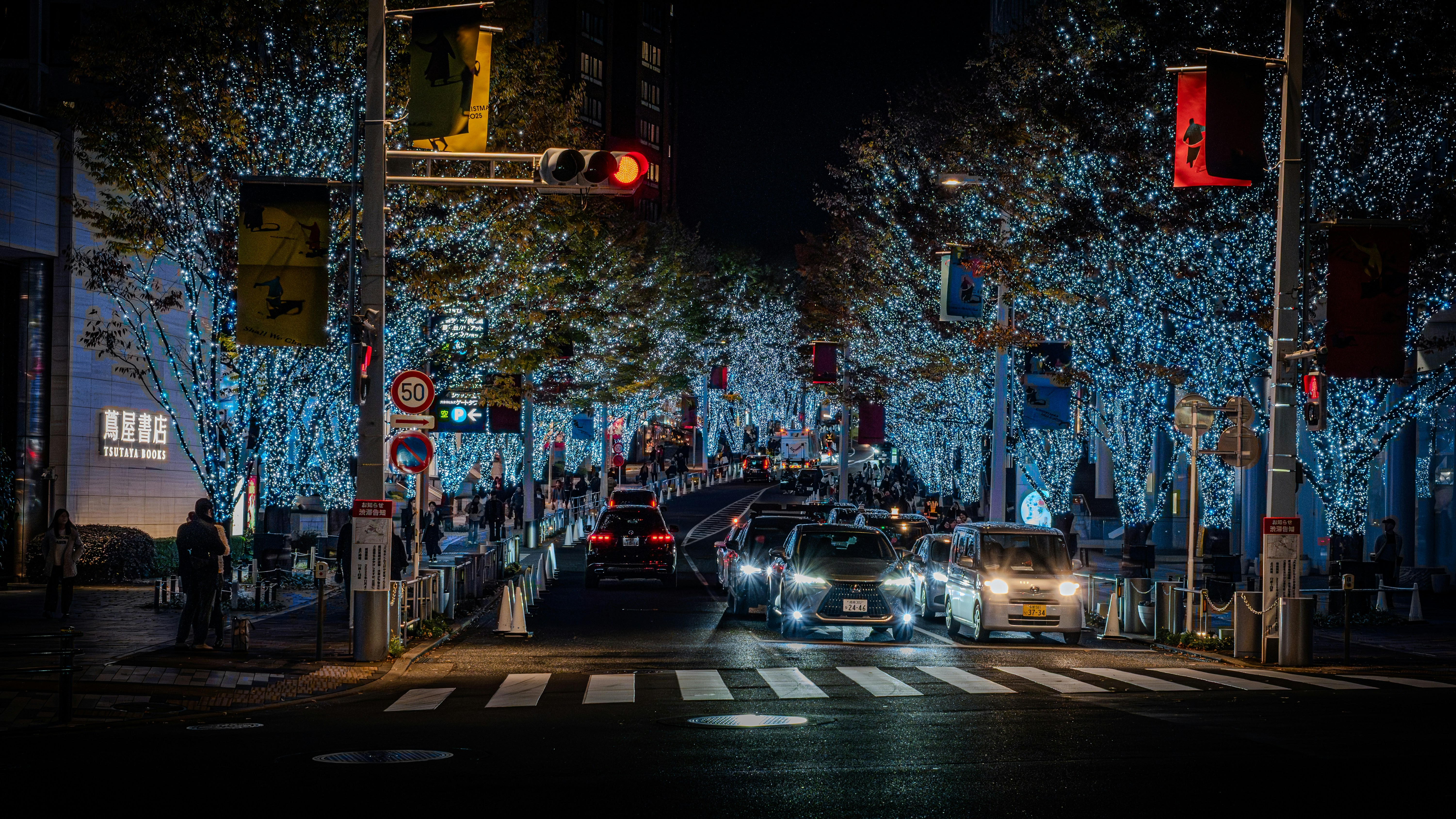 Cars drive down a street decorated with lights.