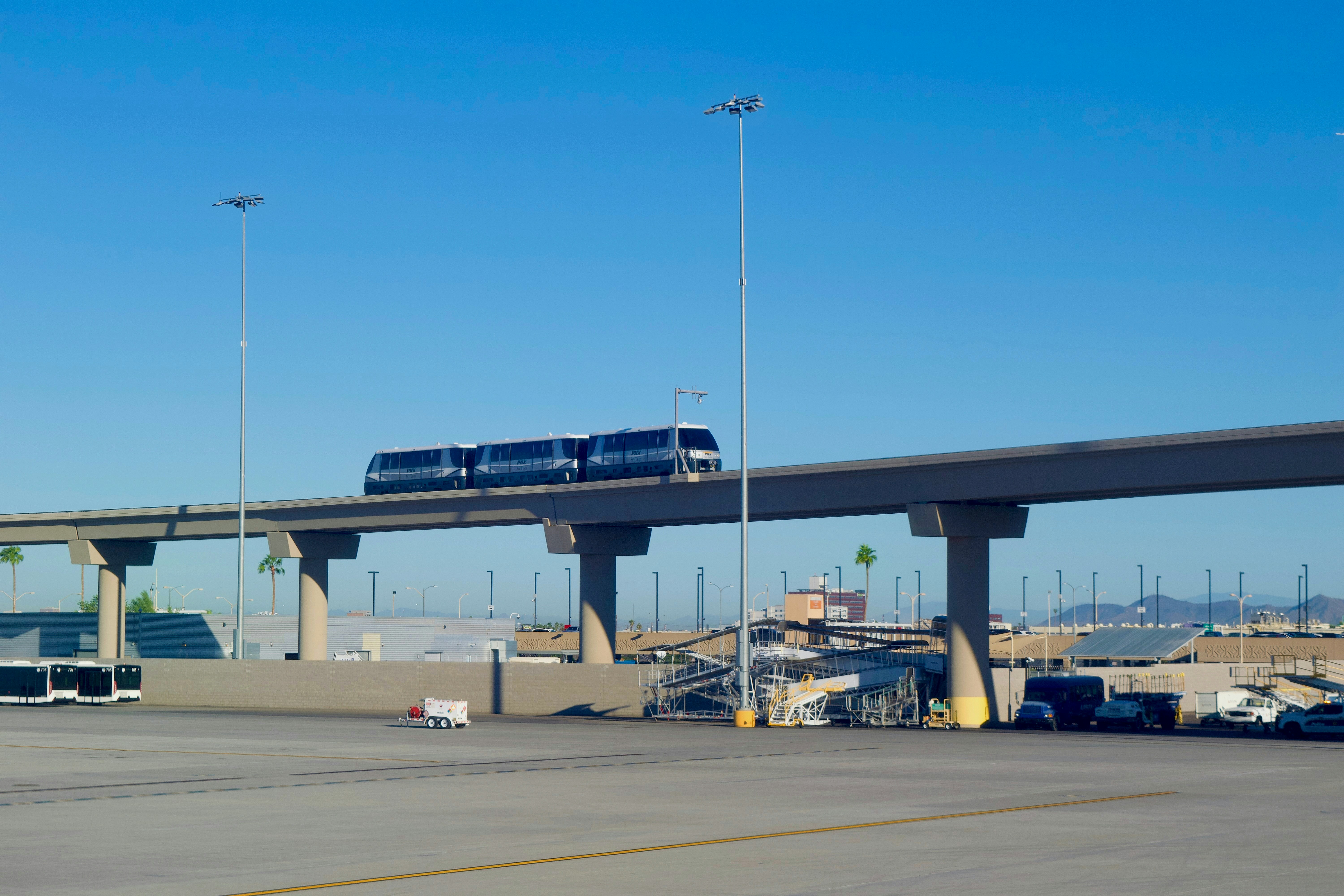 Monorail train travels on elevated track under blue sky.
