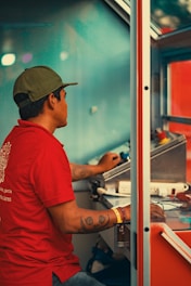 Man in red shirt operating controls inside a booth