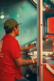 Man in red shirt operating controls inside a booth
