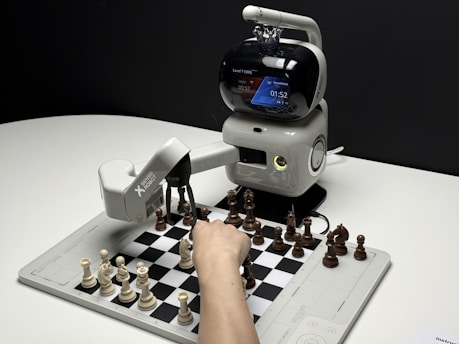 Robot arm playing chess with a human hand