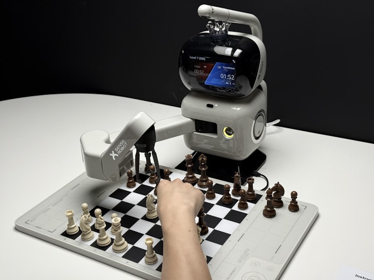 Robot arm playing chess with a human hand