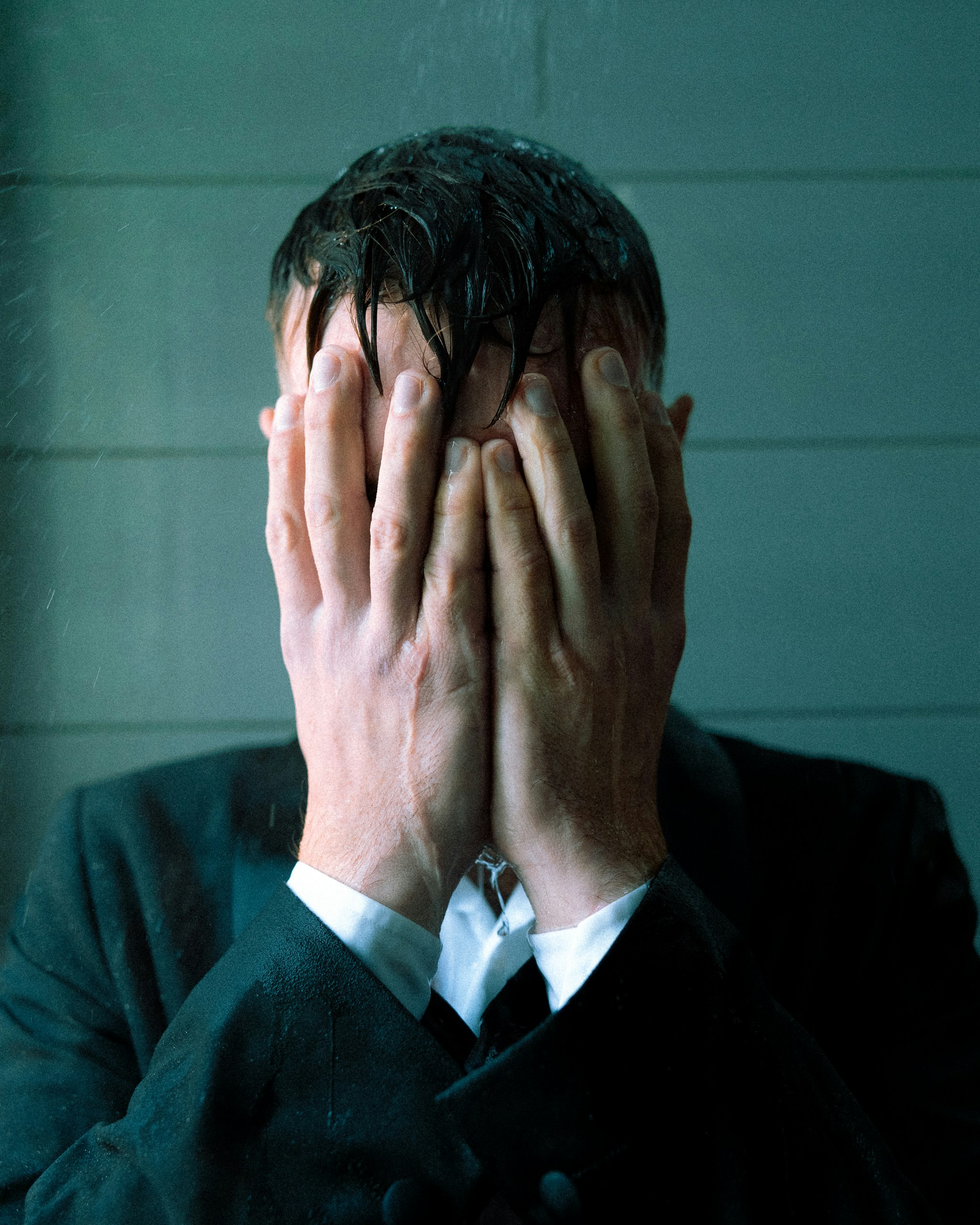Man in suit covering face with hands