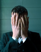 Man in suit covering face with hands