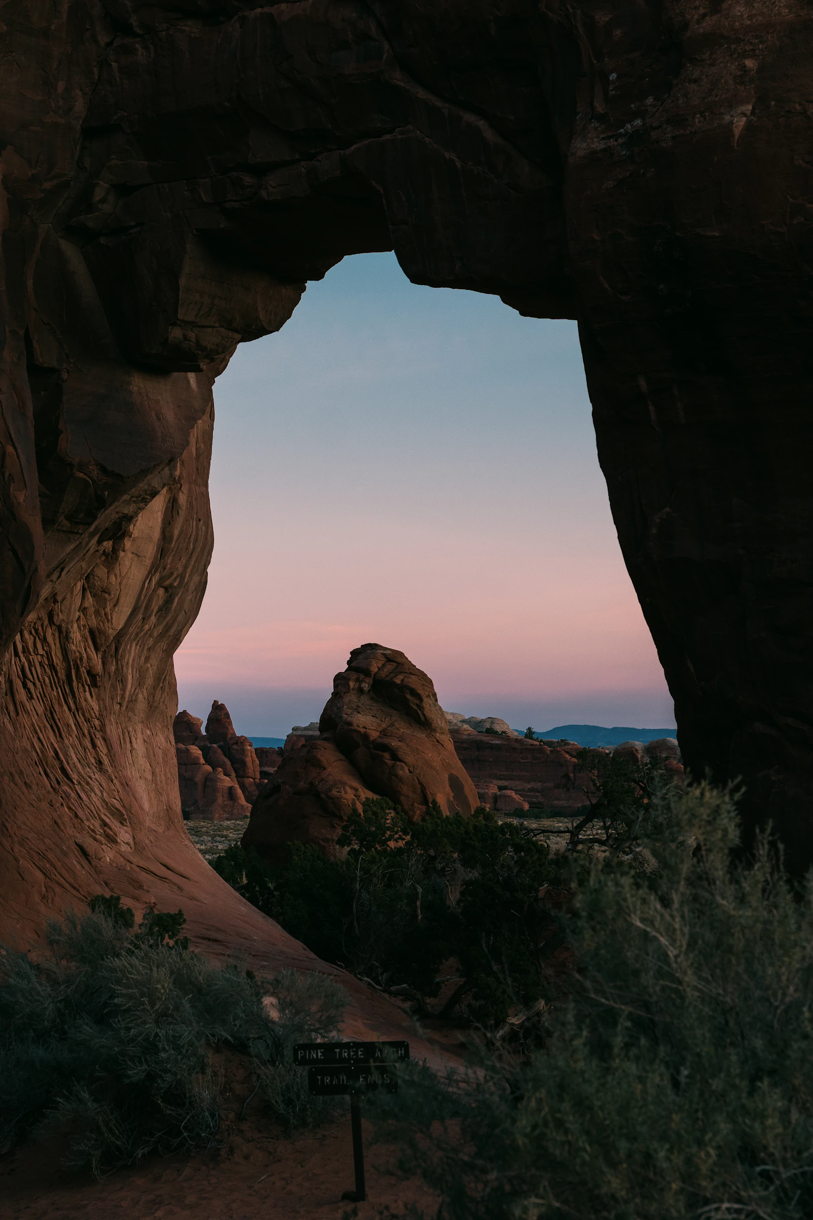 Desert rock arch framing a Southern Utah landscape at twilight