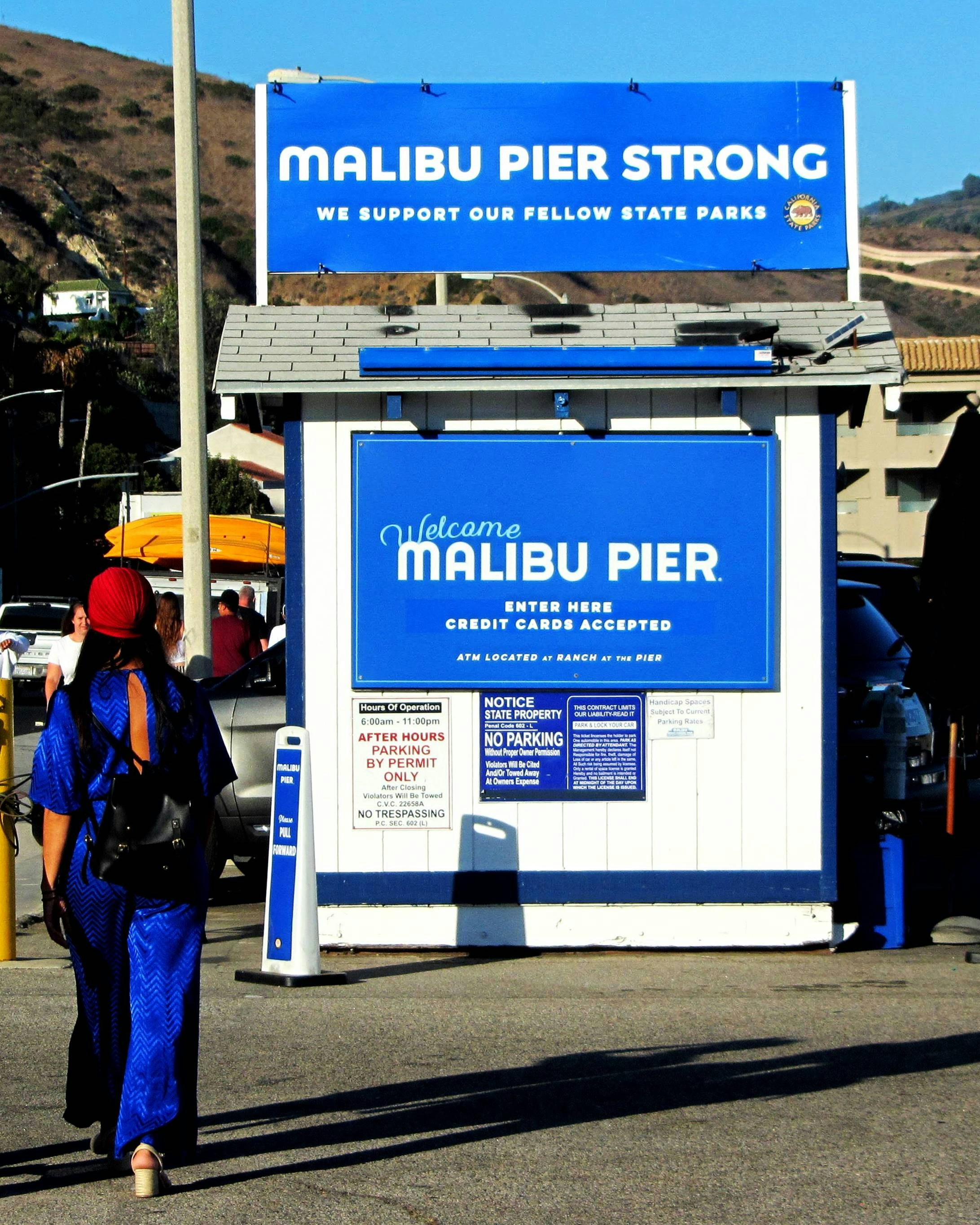 Malibu pier entrance with "malibu pier strong" sign.