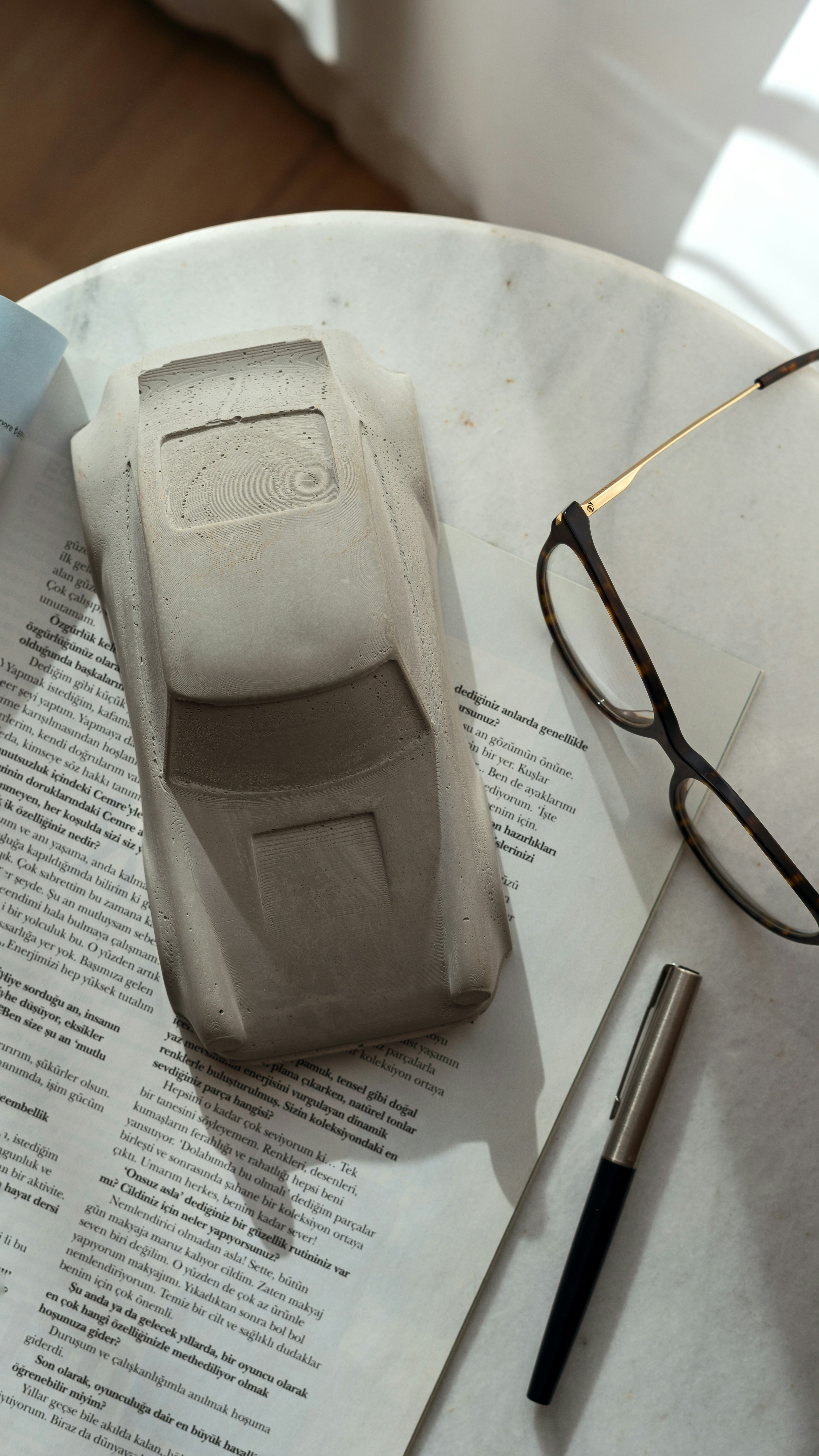 A model car, eyeglasses, and pen on a newspaper.