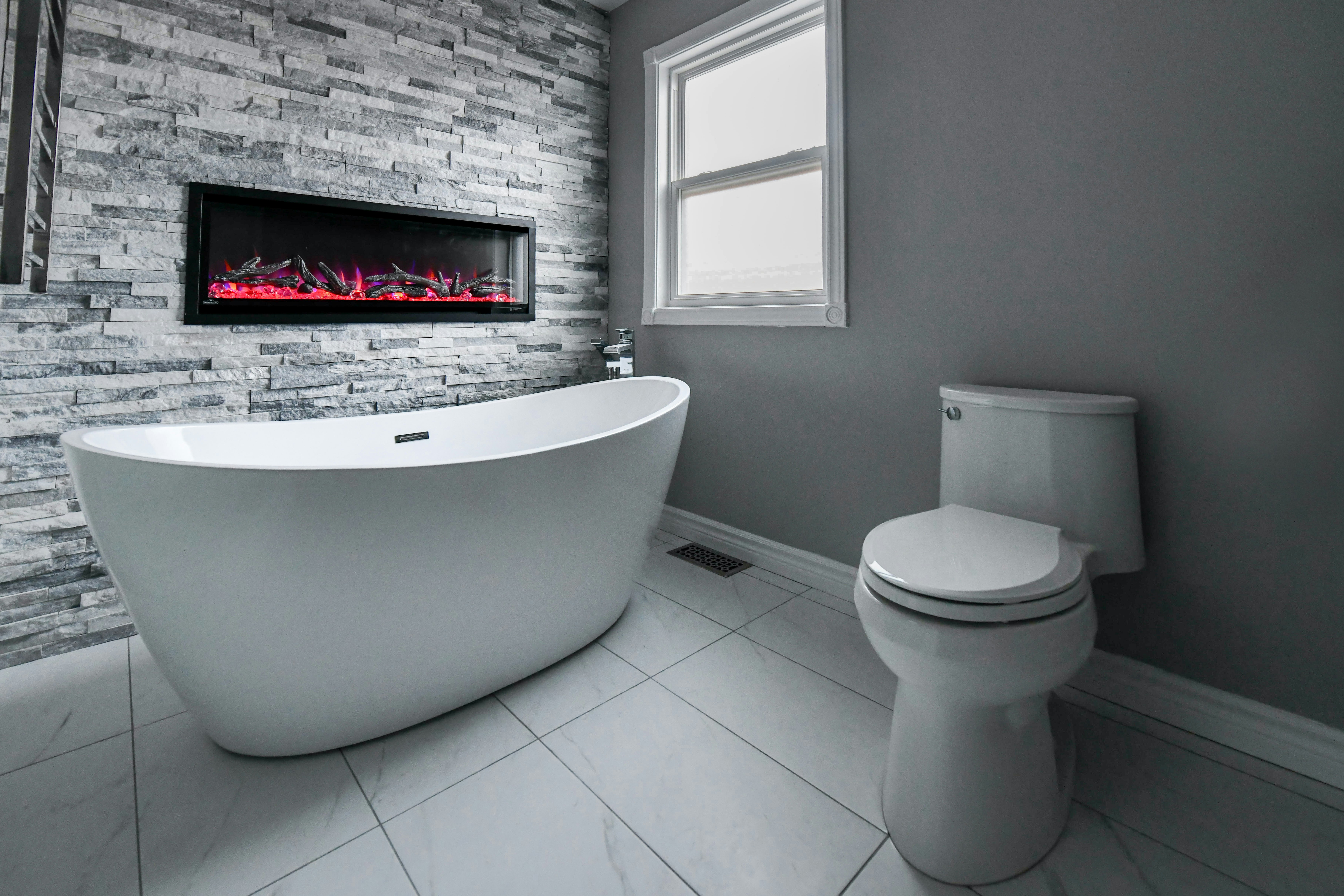 Modern bathroom with freestanding tub and fireplace.