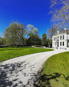 White manor house with gravel driveway and green lawn