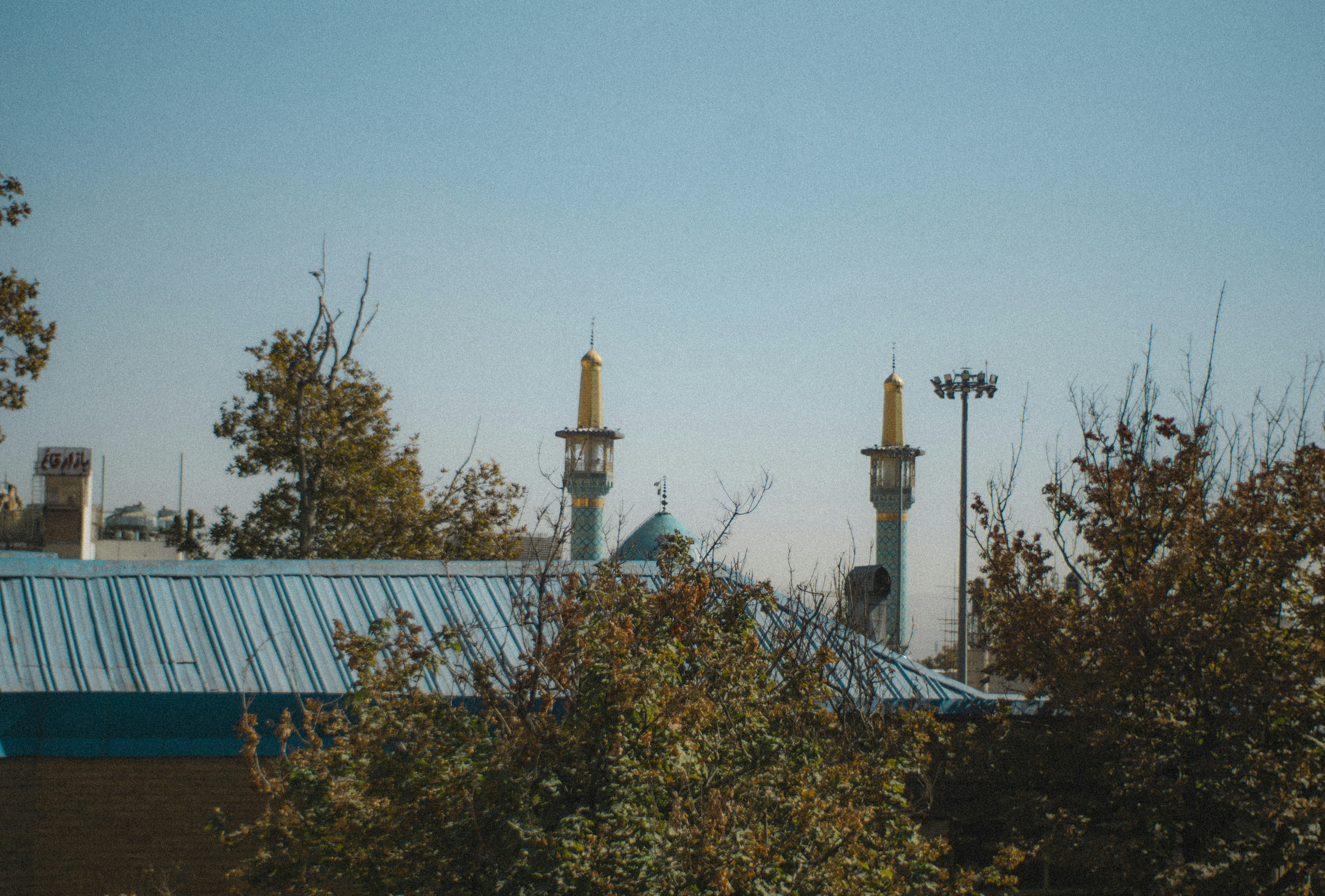 Two golden minarets rise above trees and buildings.