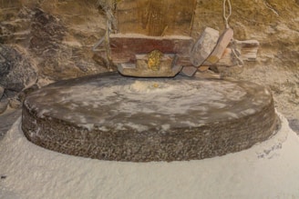 Old millstone grinding flour in a rustic setting.