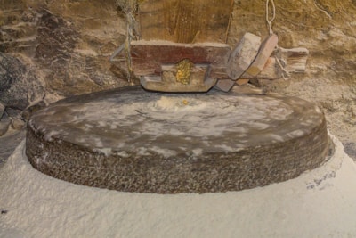 Old millstone grinding flour in a rustic setting.