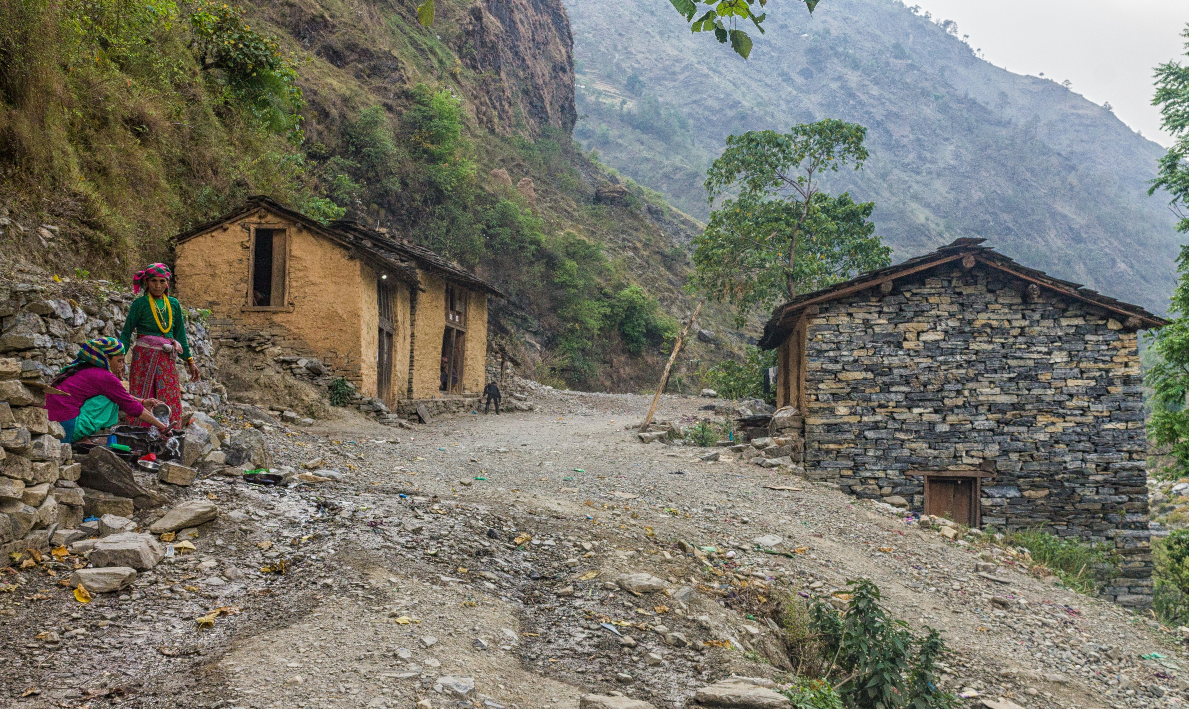 Two rustic houses on a dirt road in the mountains.