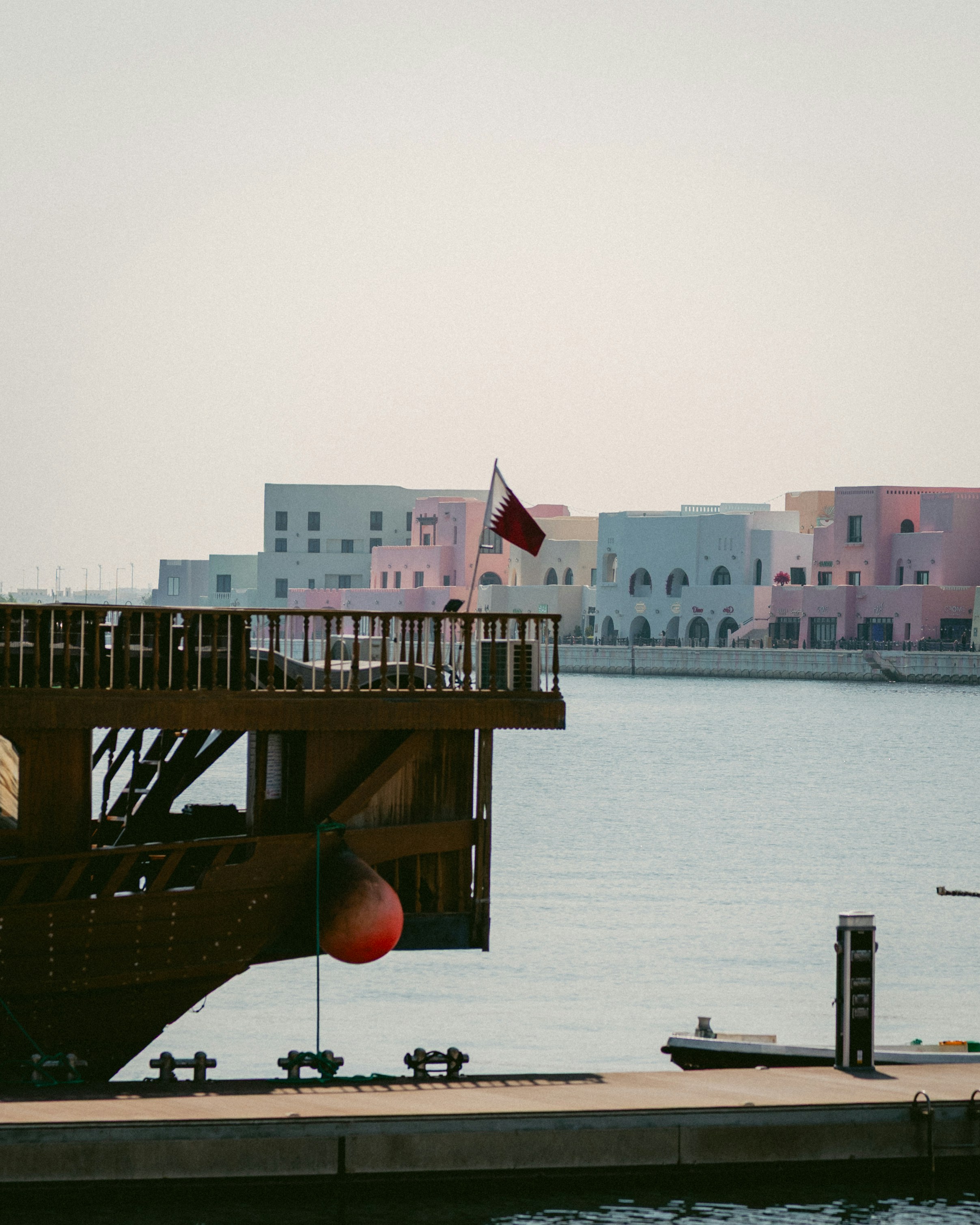 Boat docked by colorful buildings and calm water.