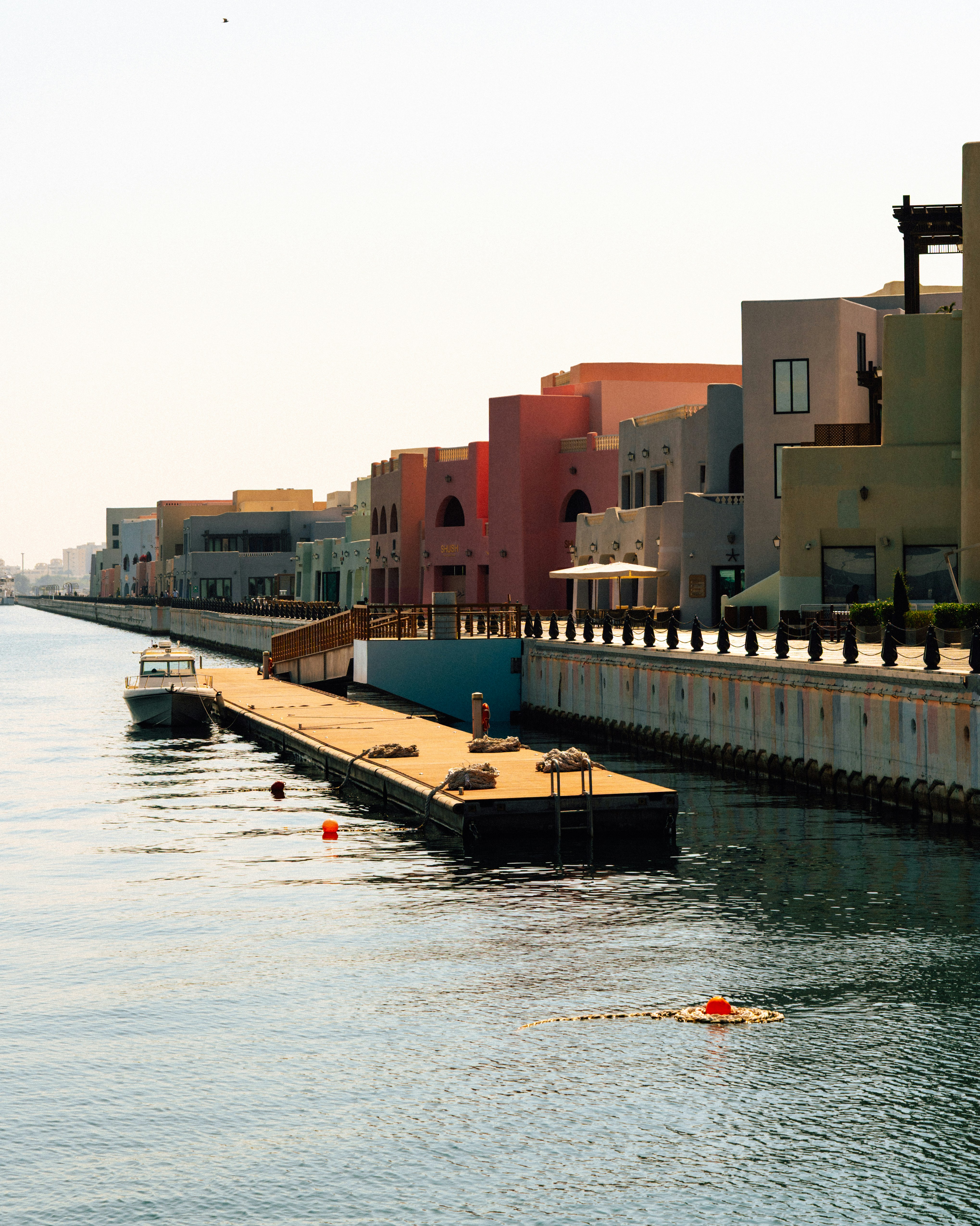 Waterfront buildings with a long pier and boat.