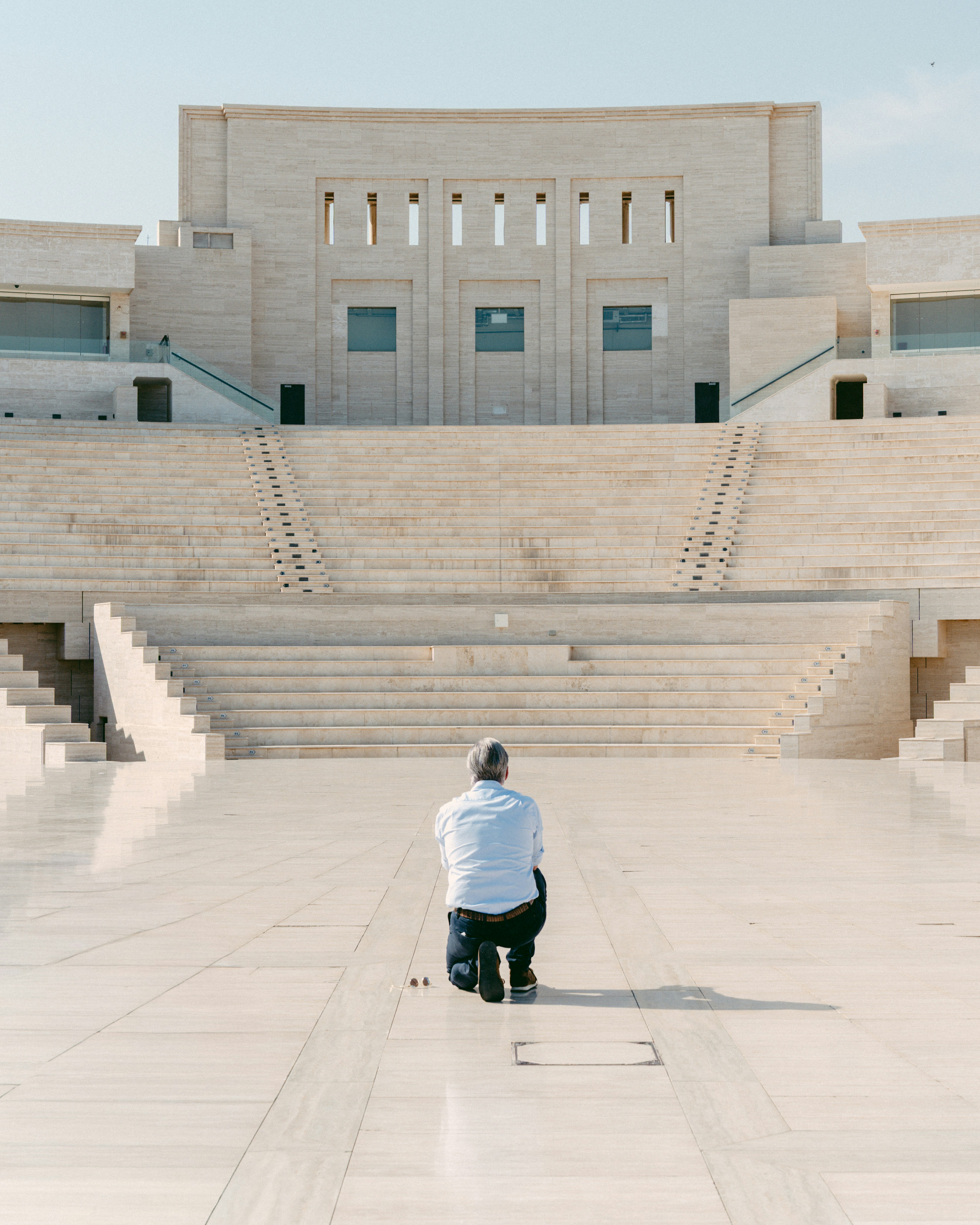 Man kneeling on steps of large modern building