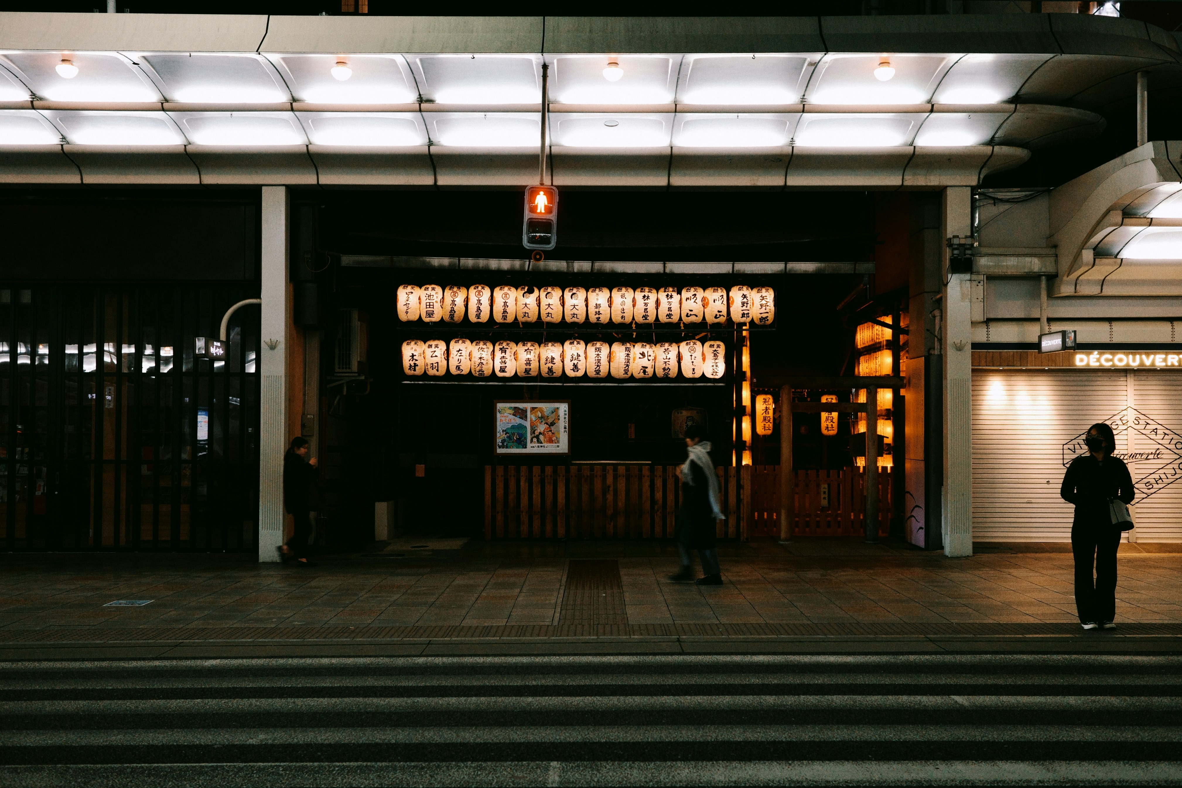 People walking past illuminated storefronts at night. photo – Free ...
