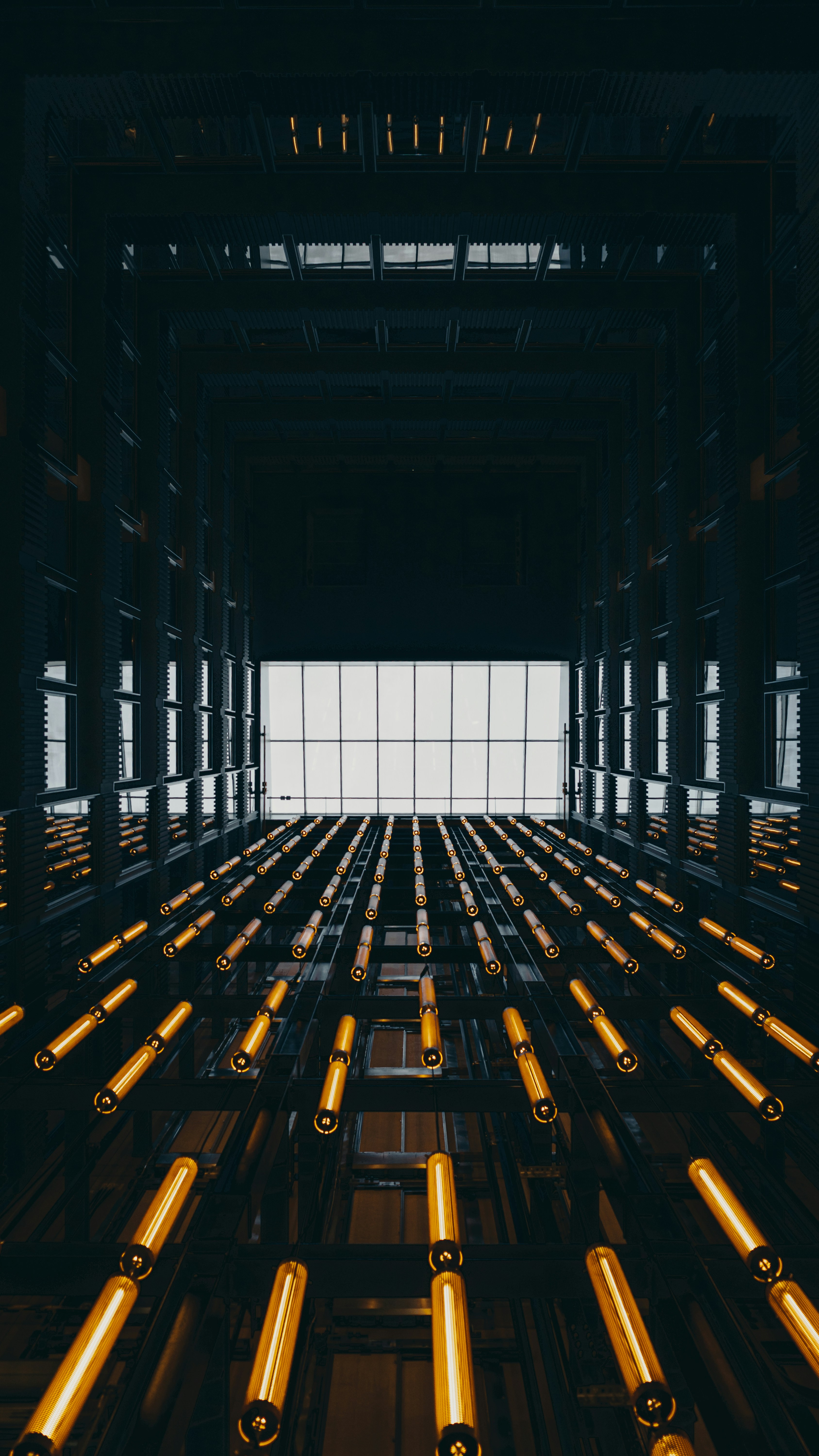 Rows of golden lights ascend towards a skylight.
