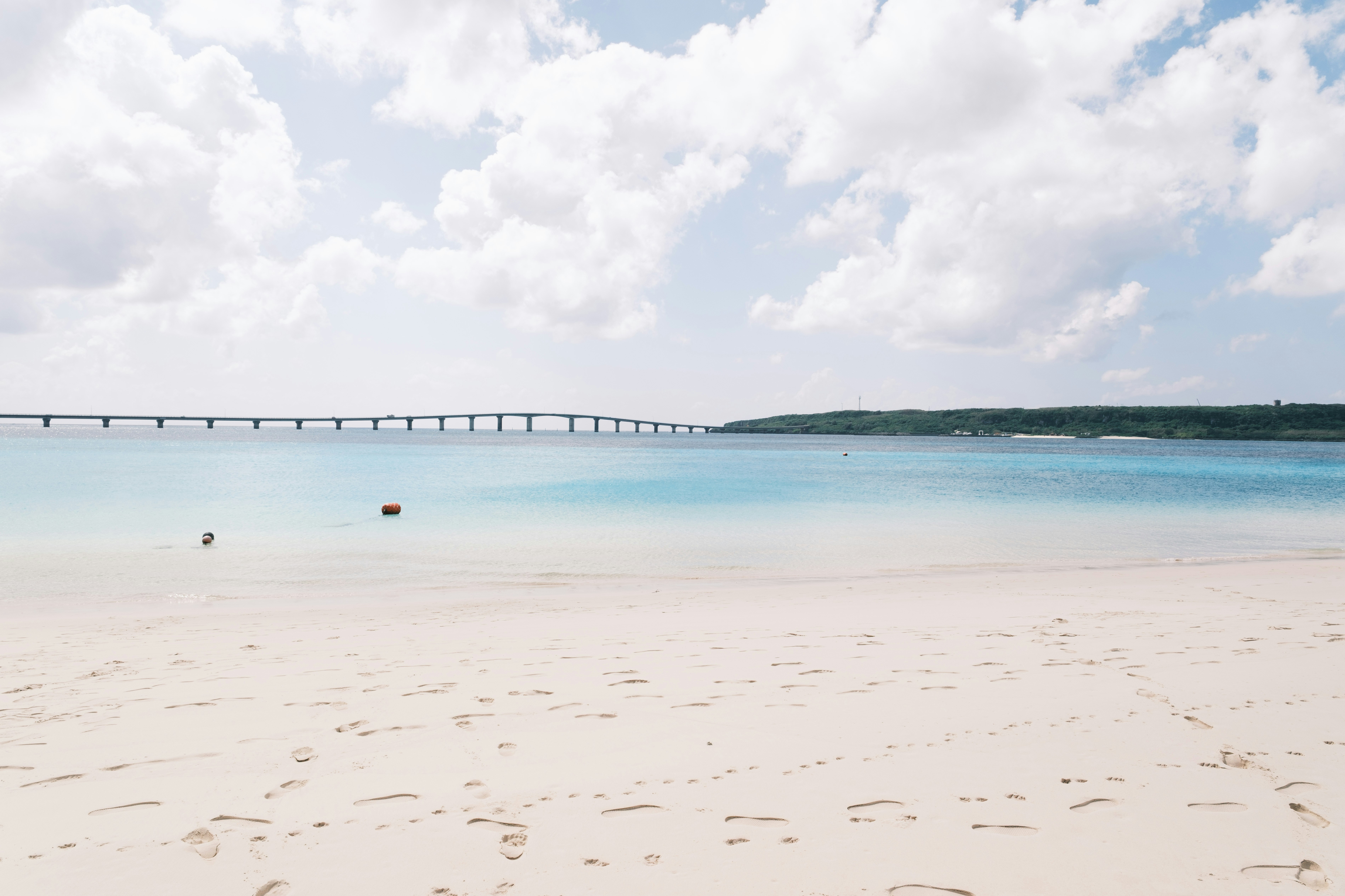 A long bridge crosses a bright blue ocean.