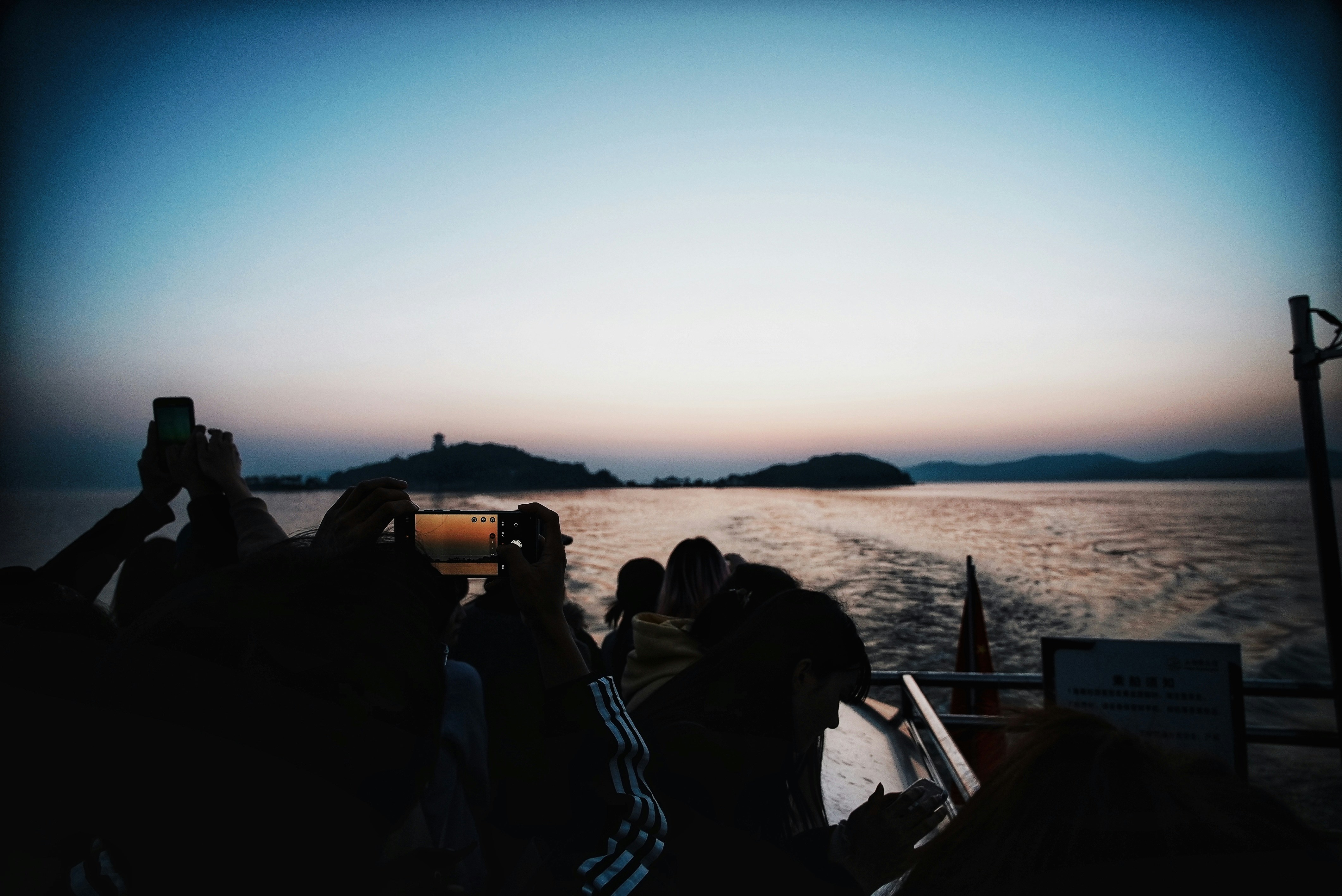People on a boat watching the sunset over water.