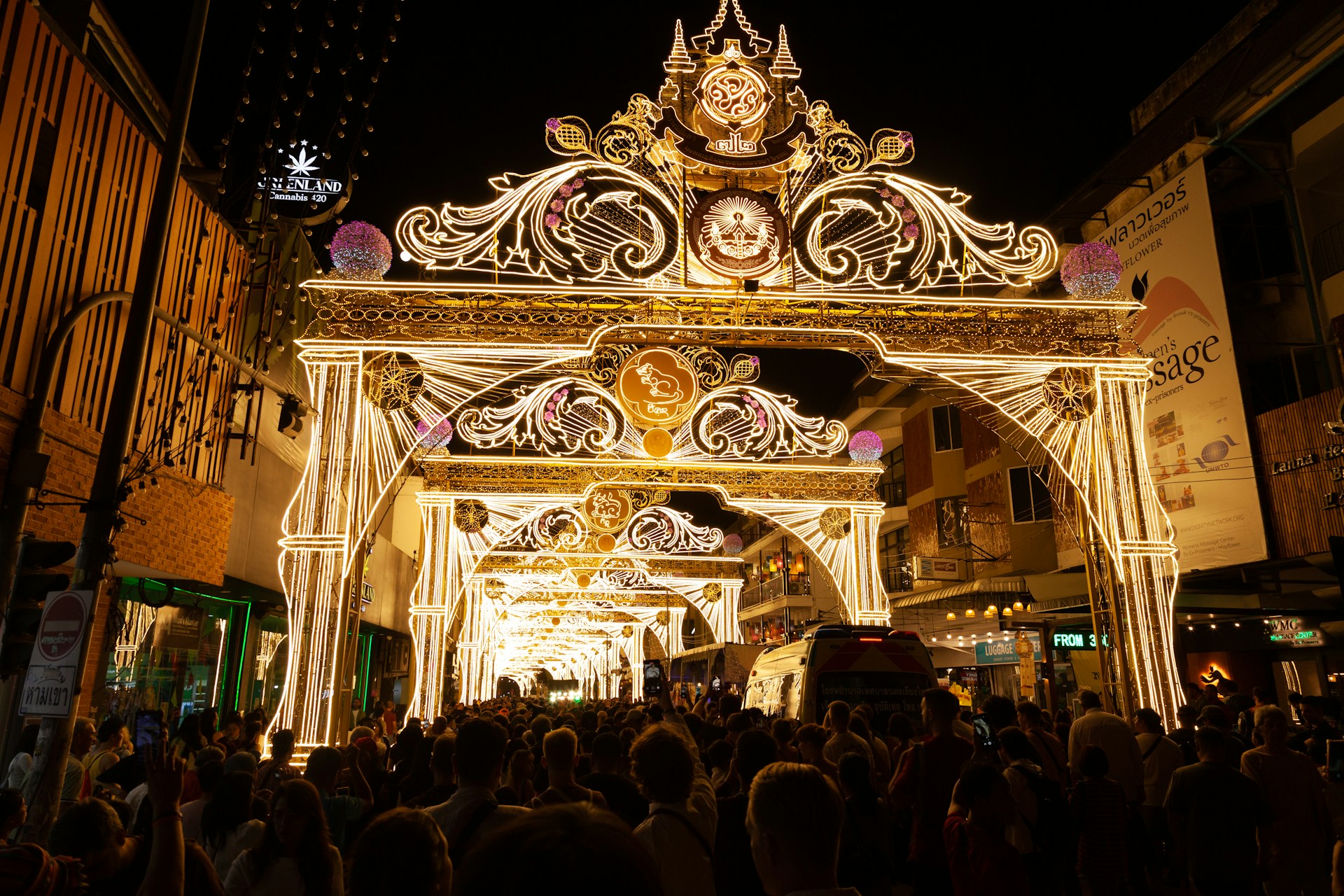 Ornate illuminated archway at night with crowd