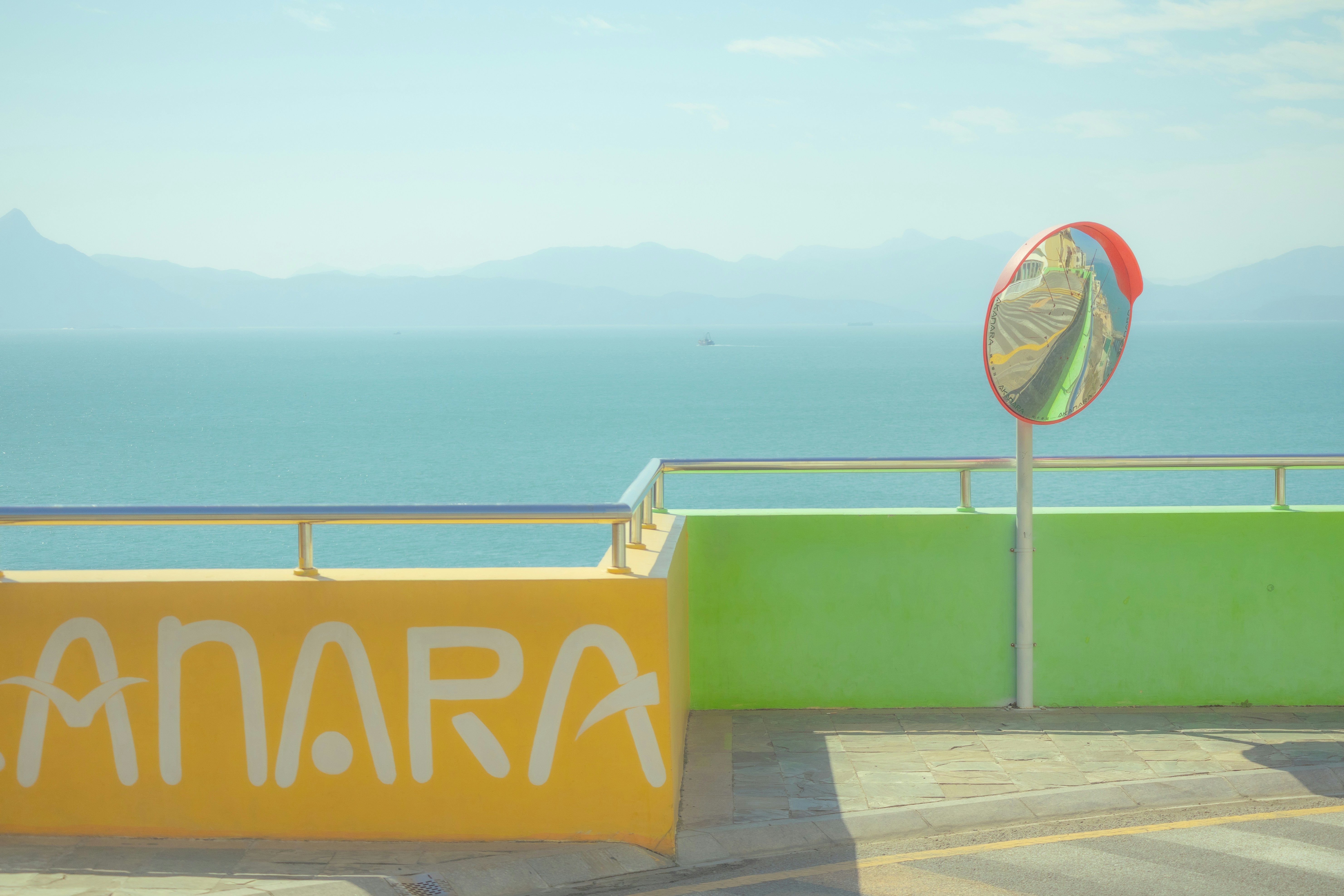 Yellow and green wall with a mirror overlooking the sea