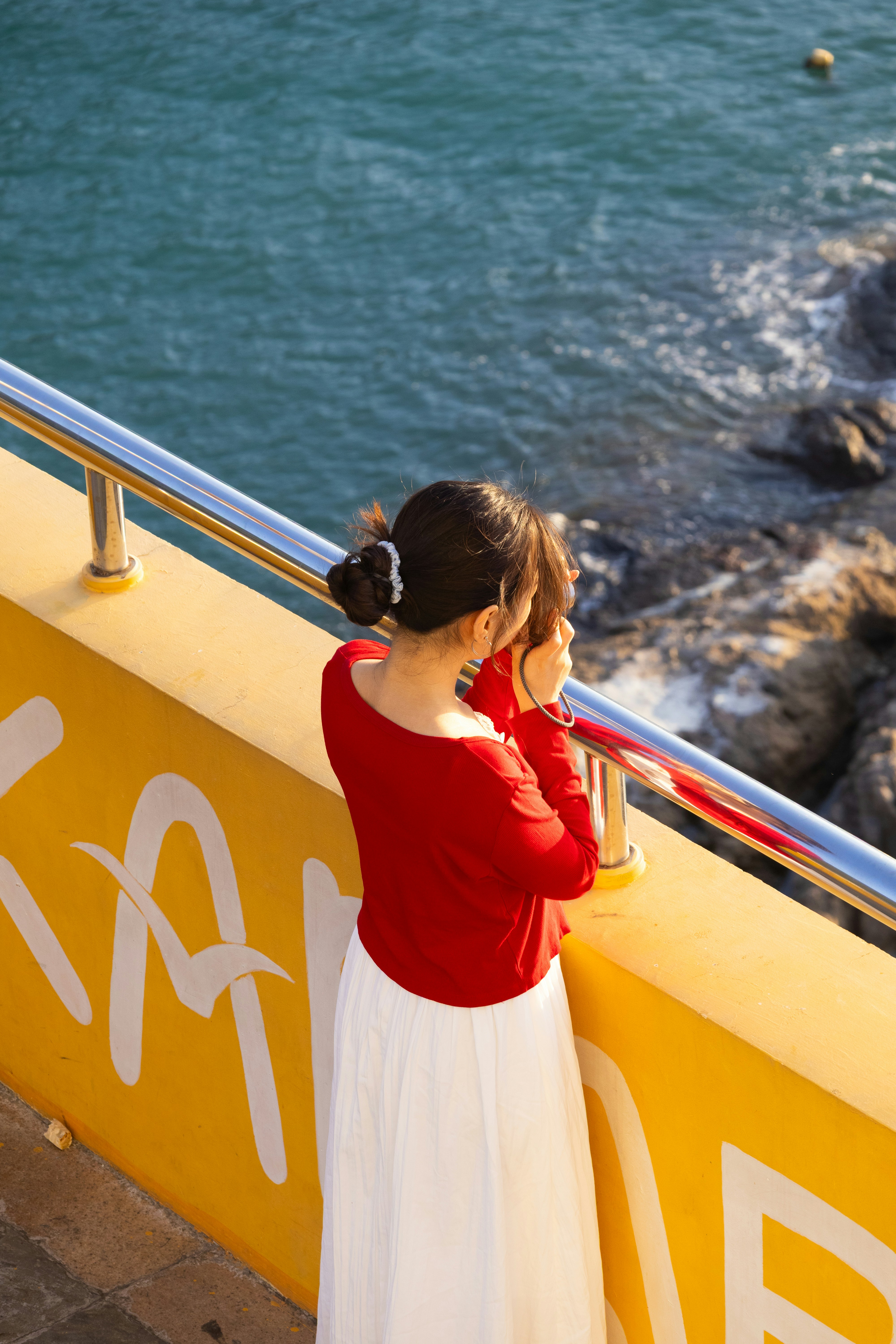 Woman in red top looks at the ocean