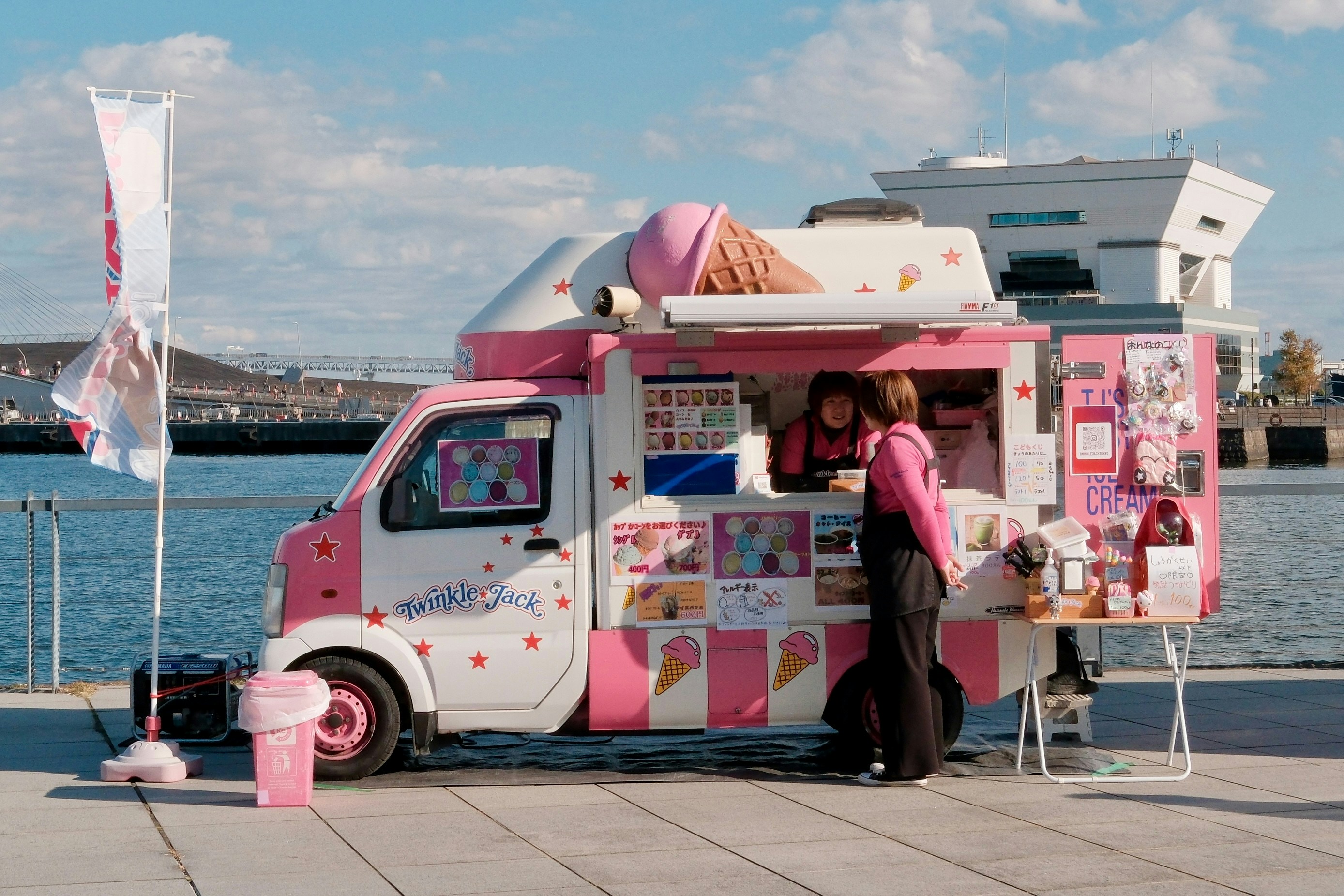 Pink ice cream truck serving customers by the water