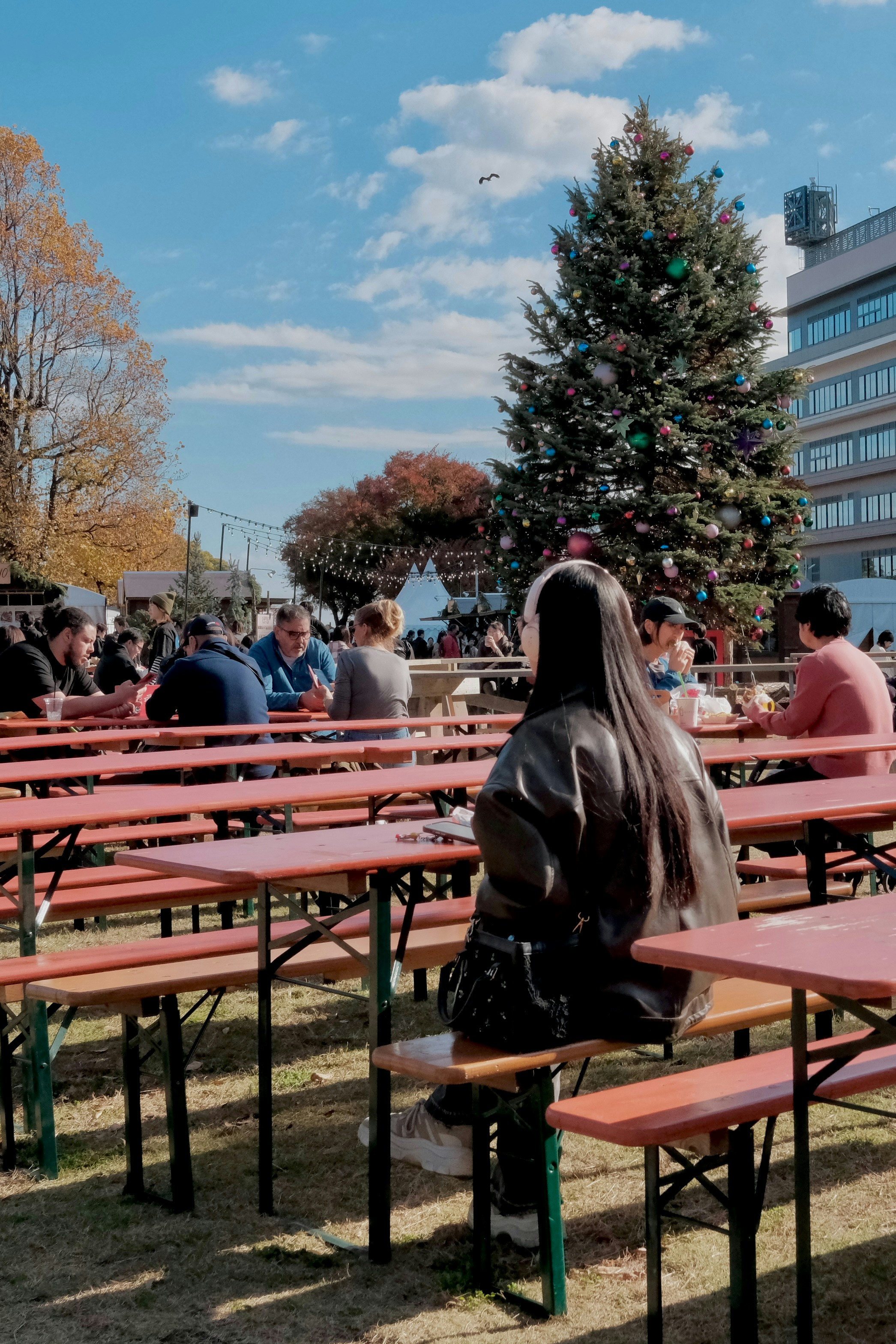 People sitting at tables near a decorated christmas tree.