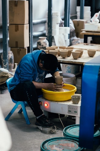 Man working on a pottery wheel creating ceramics.