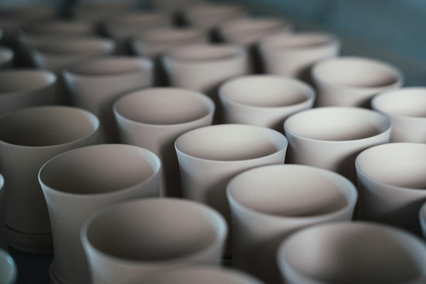 Des tasses en céramique blanche alignées avant cuisson